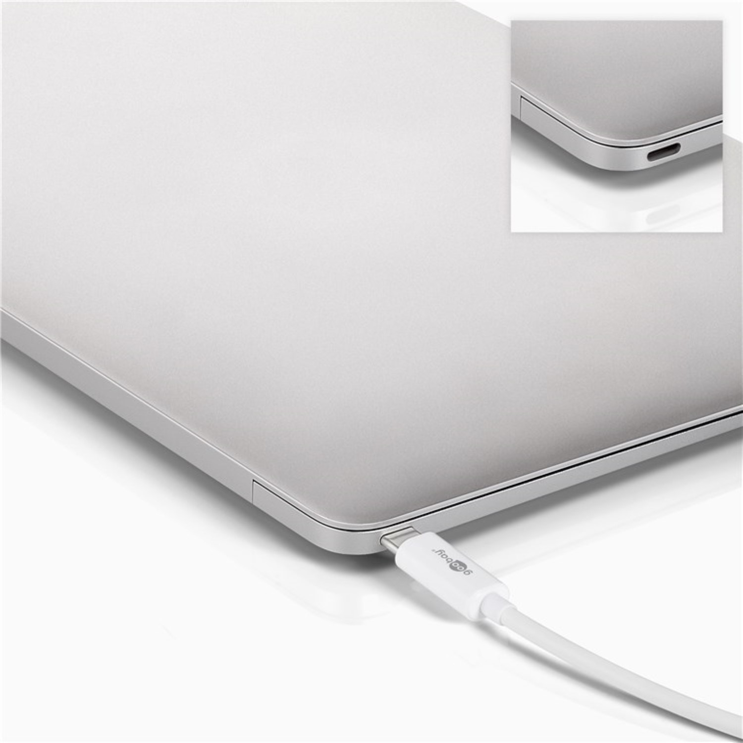 Silberner Laptop mit eingestecktem weißen Ladekabel. Nahaufnahme des Ladeanschlusses.