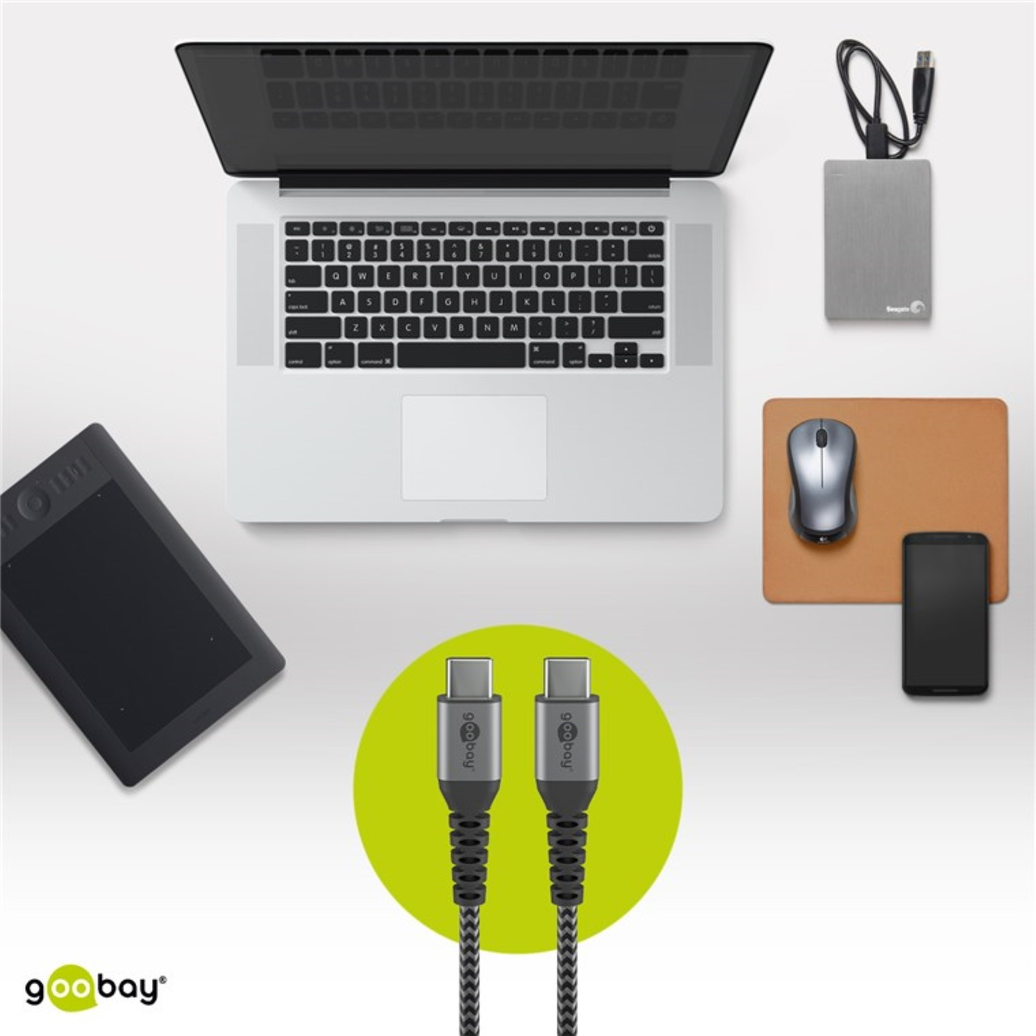 Laptop, dysk zewnętrzny, mysz, telefon i dwa kable USB-C na białej powierzchni.