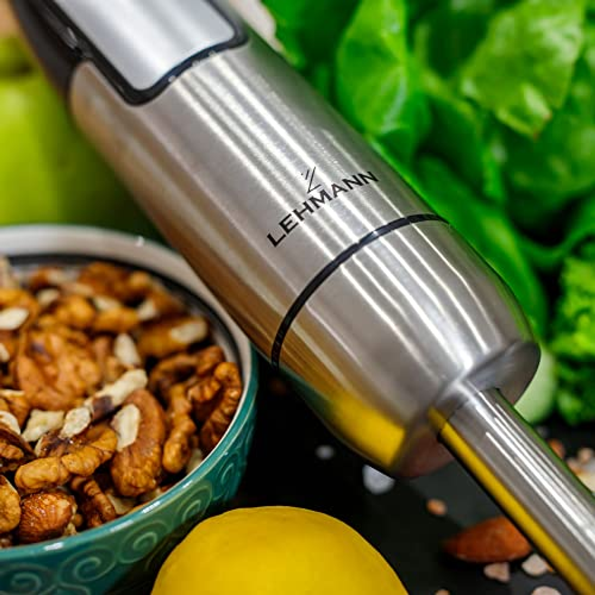 Frullatore a immersione con lama in acciaio inox e ingredienti: noci, limone, verdure.
