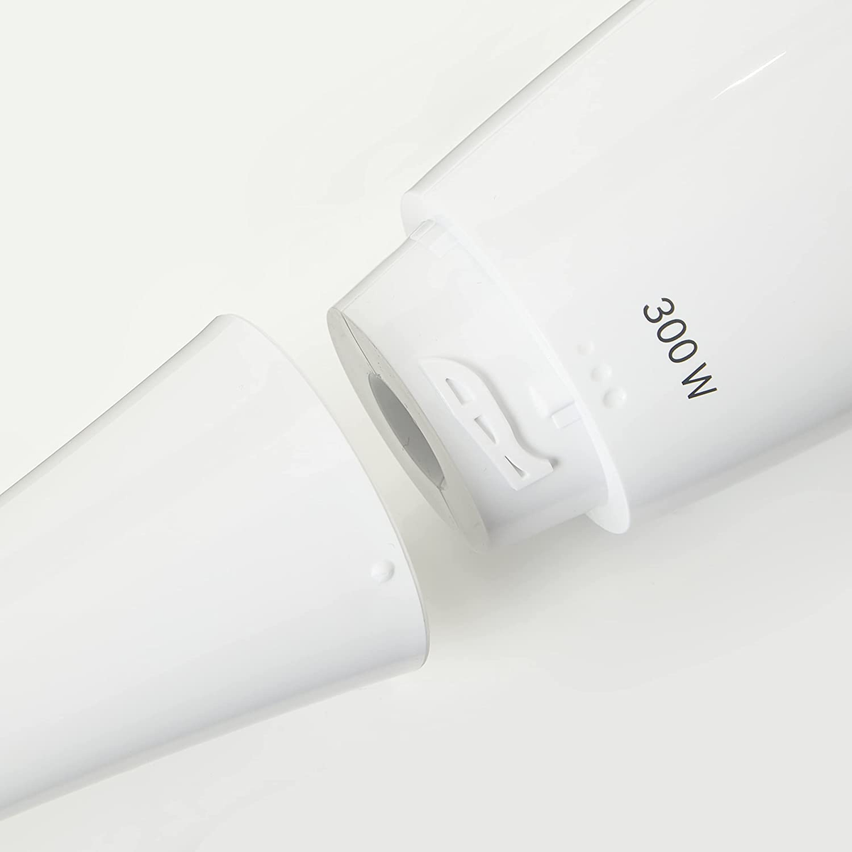 Parti di un frullatore a immersione bianco staccate, con l'etichetta '300 W' sulla superficie bianca.