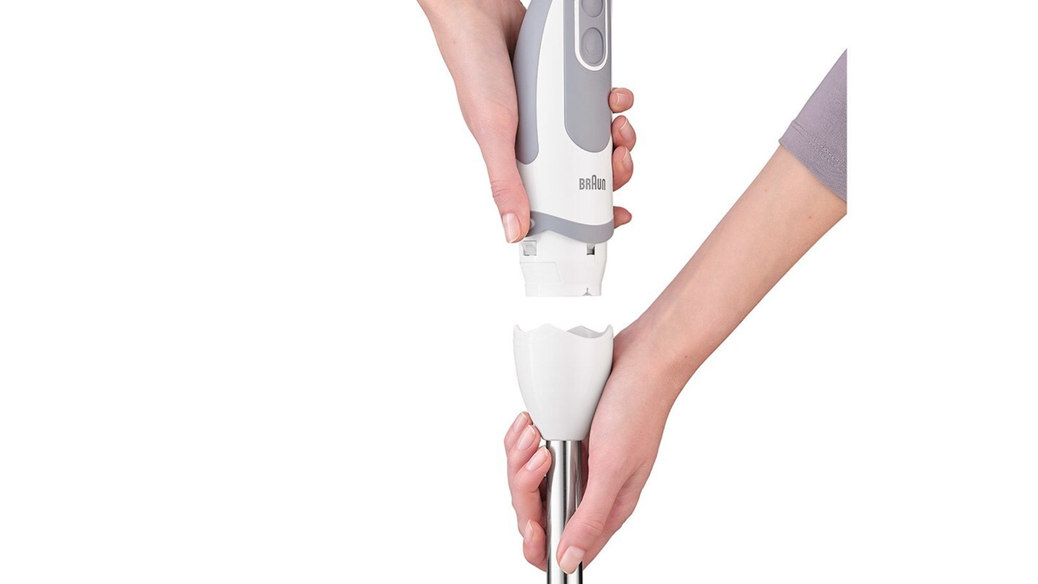 Hände, die einen weißen Braun-Handmixer zusammensetzen. Weiße Oberfläche.
