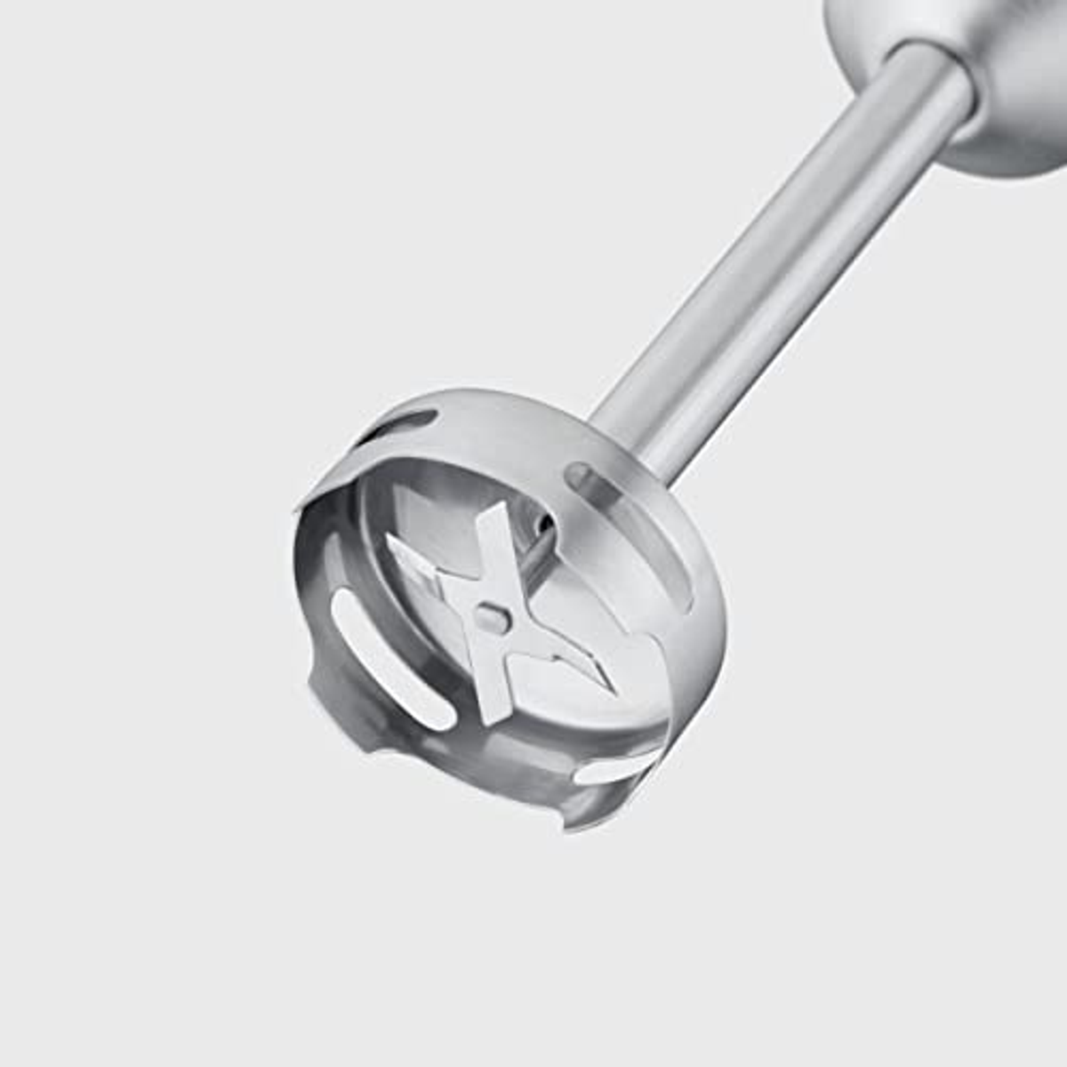 A silver immersion blender head with blades. The blades are inside of a round metal base.