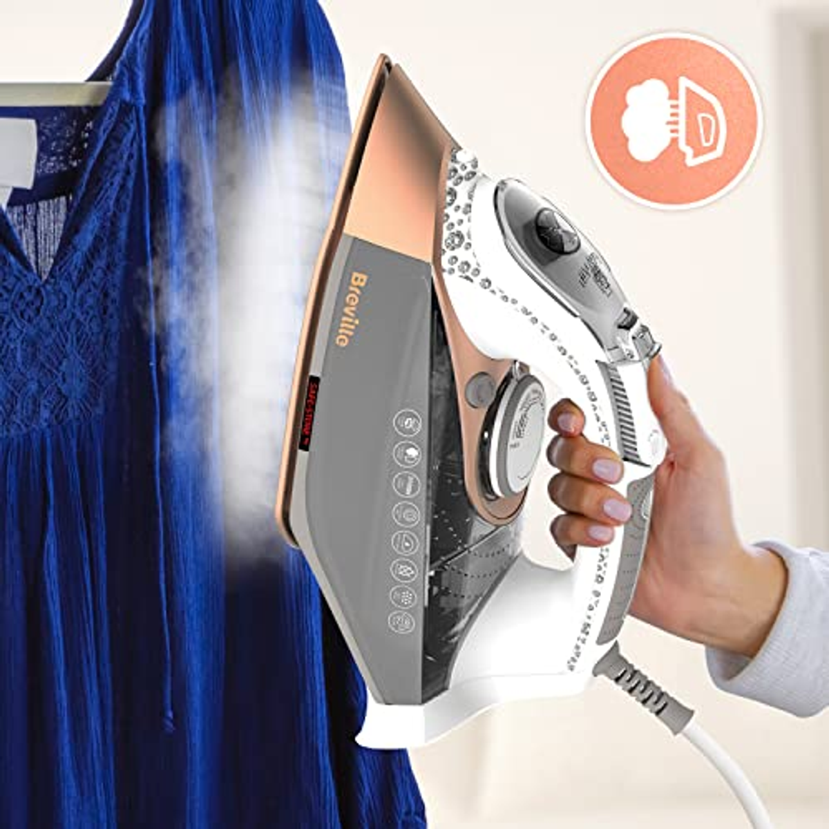 Eine Hand bügelt ein blaues Kleid mit einem weißen und kupferfarbenen Bügeleisen.