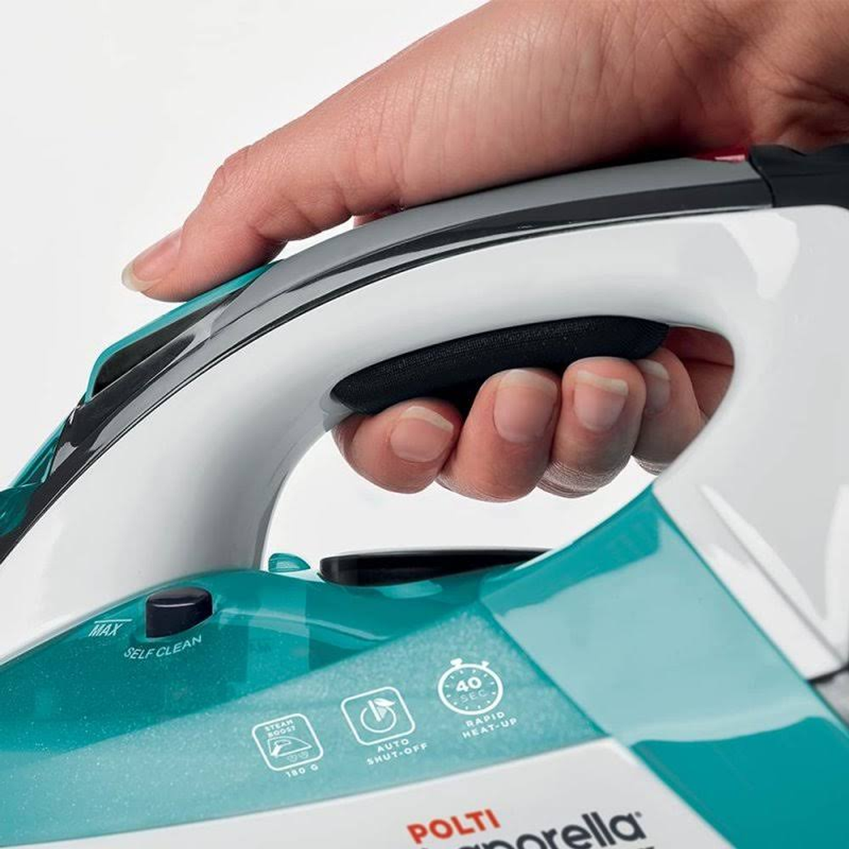 Zbliżenie na uchwyt żelazka w kolorze turkusowym i białym. Dłoń trzyma uchwyt.