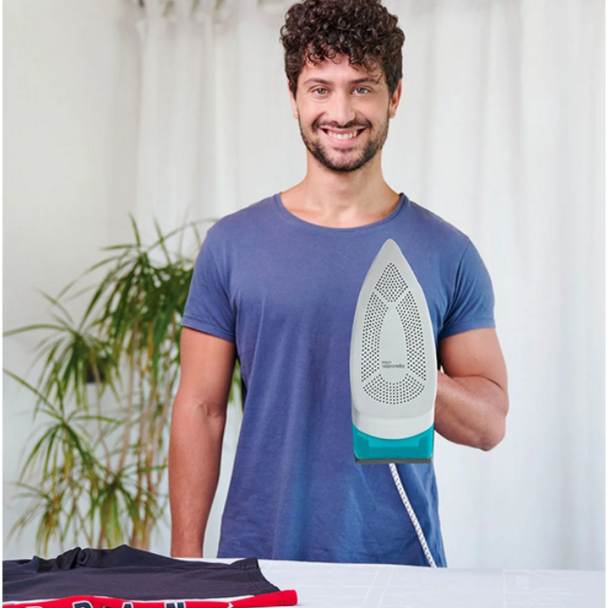 Mężczyzna trzymający żelazko nad stołem z koszulą.