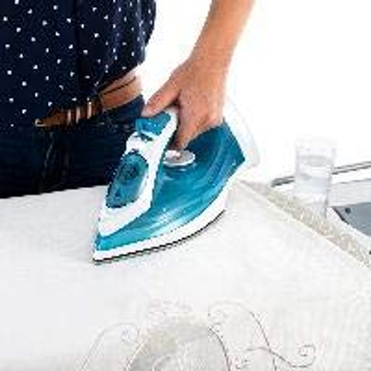 Persona planchando tela blanca con plancha azul y blanca en una tabla de planchar.