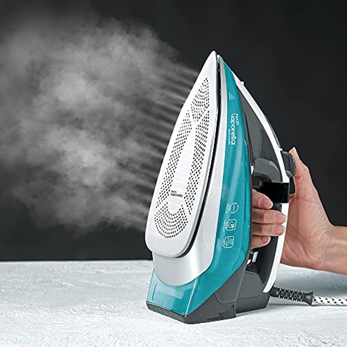 Żelazko parowe w akcji. Białe, turkusowe i szare żelazko z wydzielaniem pary.