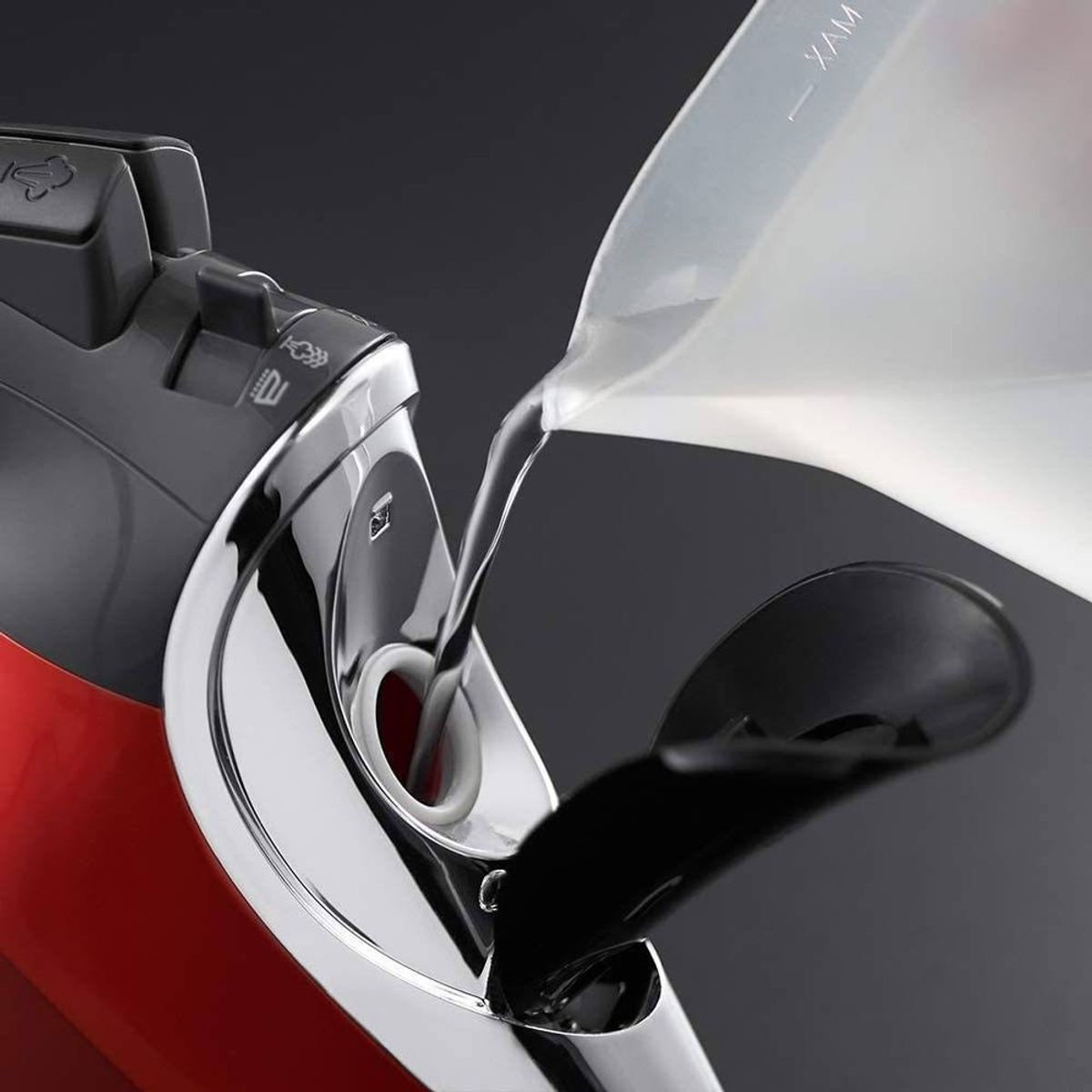 Woda jest wlewana do wlotu wody czerwonego żelazka. Żelazko jest czarne i srebrne.