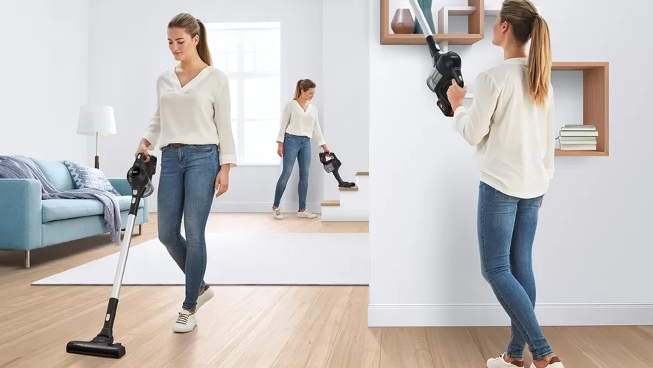 Mujer aspirando una sala con una aspiradora de mano. Otra mujer en el fondo.