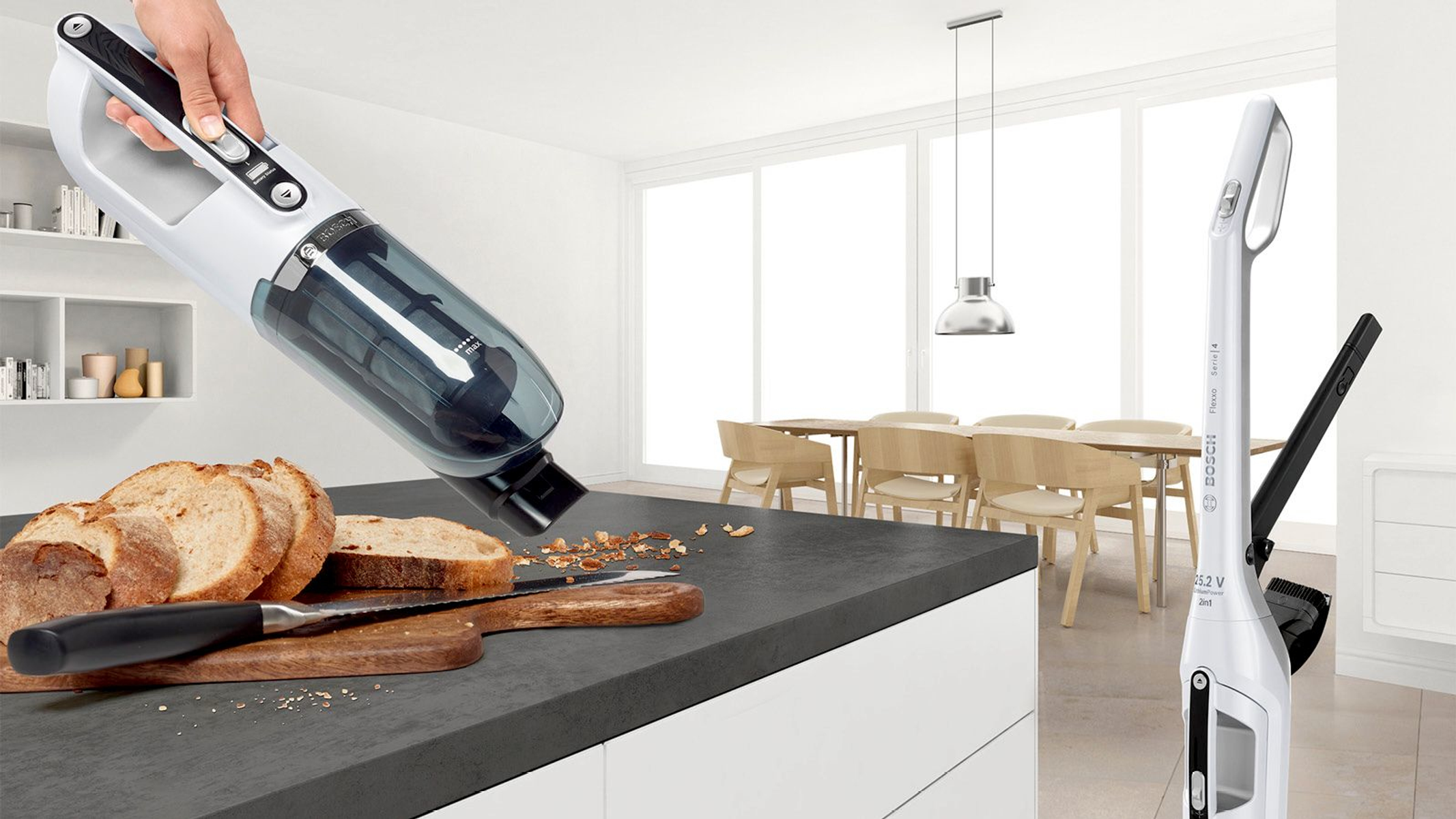 Aspiradora de mano en una encimera de cocina junto a pan y una tabla de cortar.