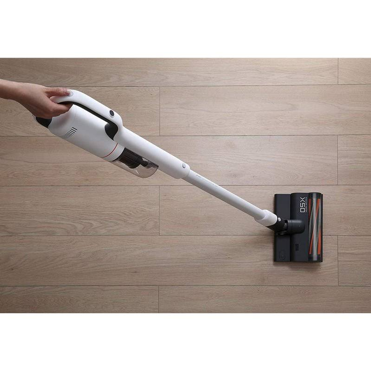 Aspirapolvere portatile bianco che pulisce un pavimento in legno.