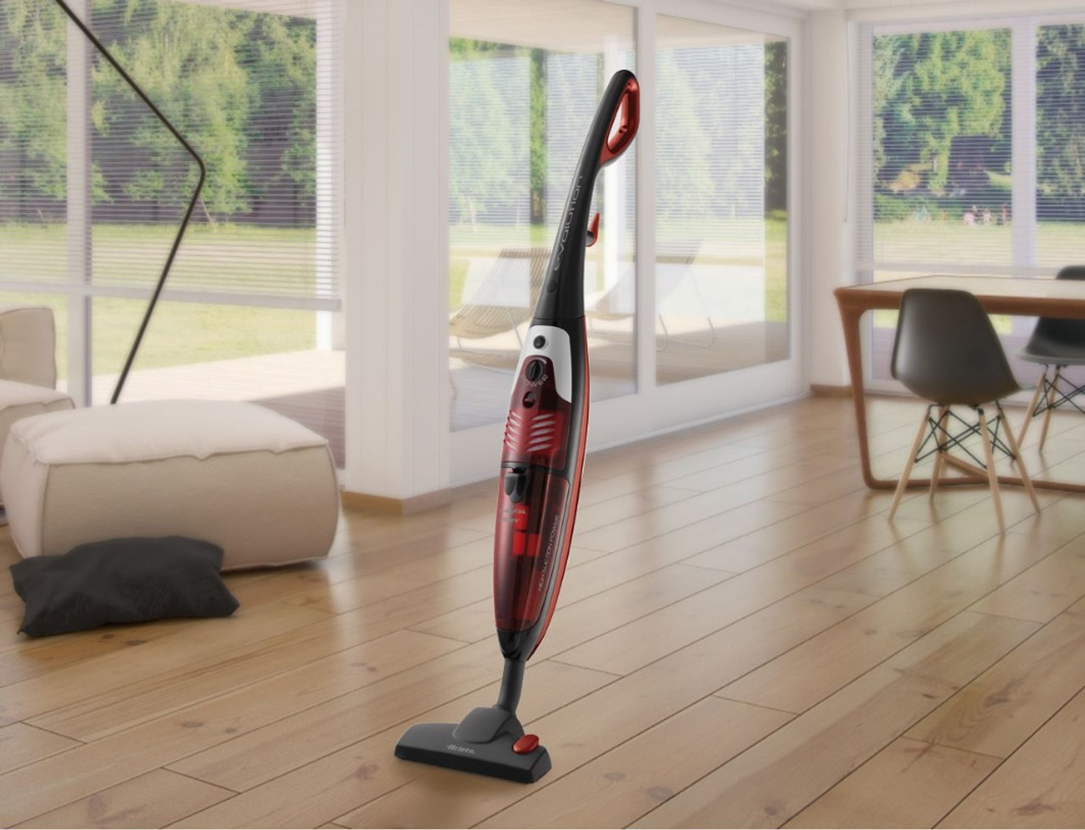 Czerwono-czarny odkurzacz Ariete stojący na drewnianej podłodze. W tle salon.