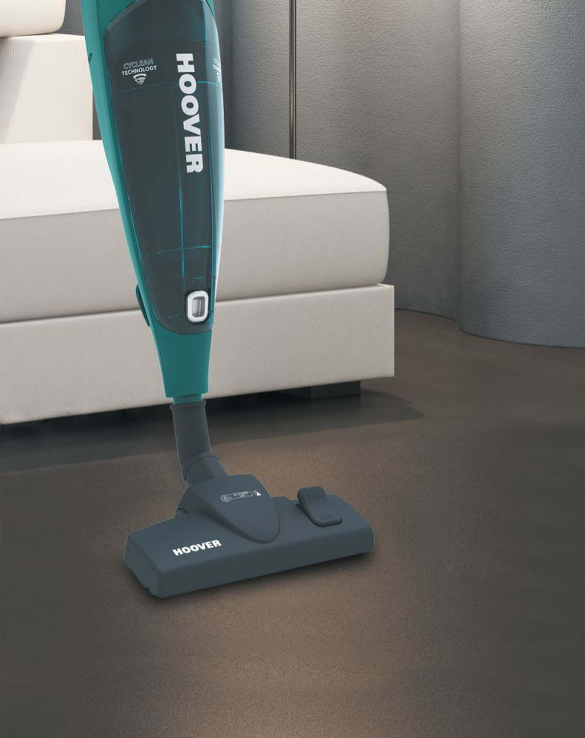 Un aspirapolvere HOOVER verde e nero su un pavimento marrone scuro. Lo sfondo è sfocato.