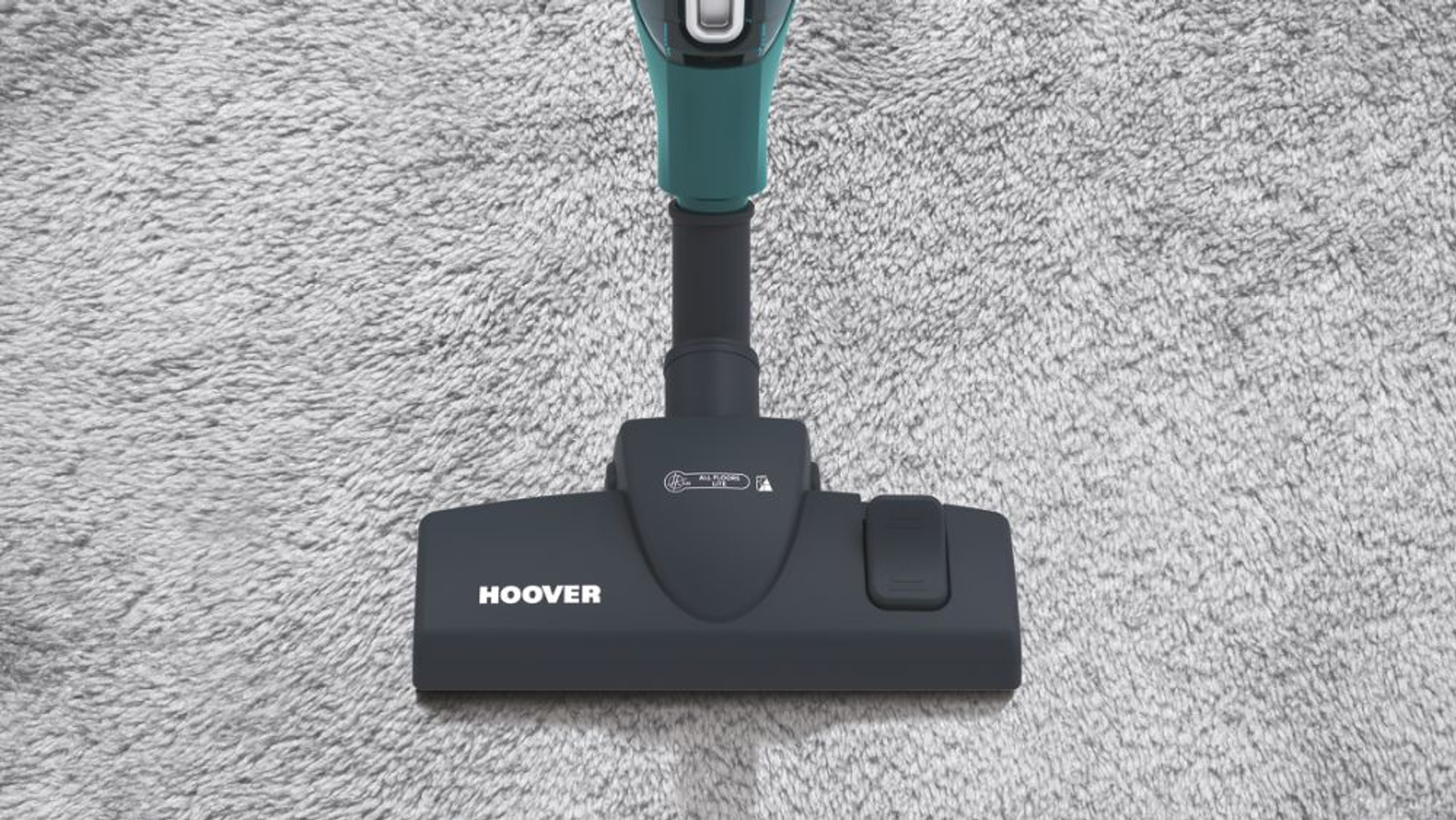 Ripresa ravvicinata di una testa di aspirapolvere Hoover nera su un tappeto grigio.