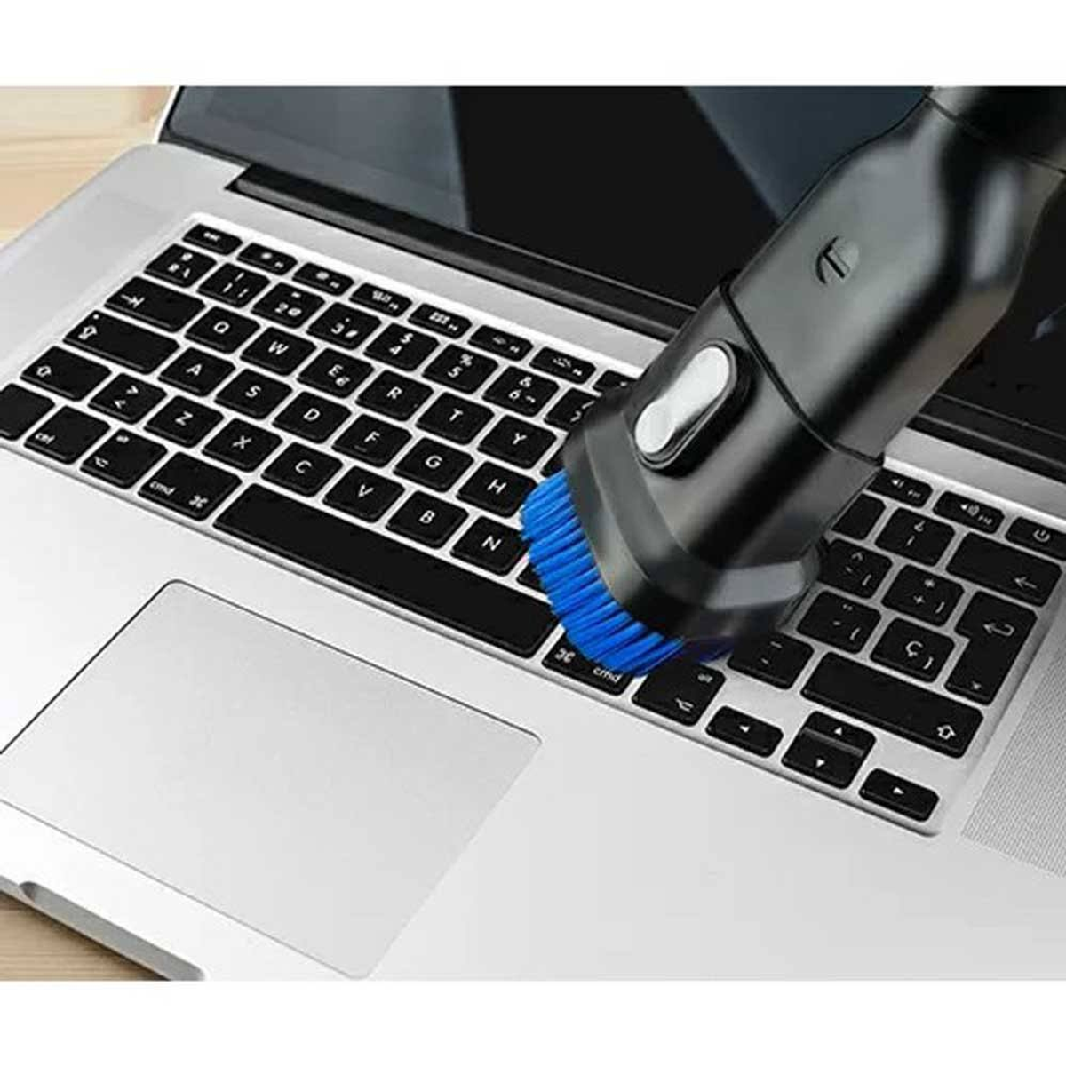 Ein Laptop, der mit einer Bürste gereinigt wird. Die Bürste ist blau und schwarz und berührt die Tastatur.