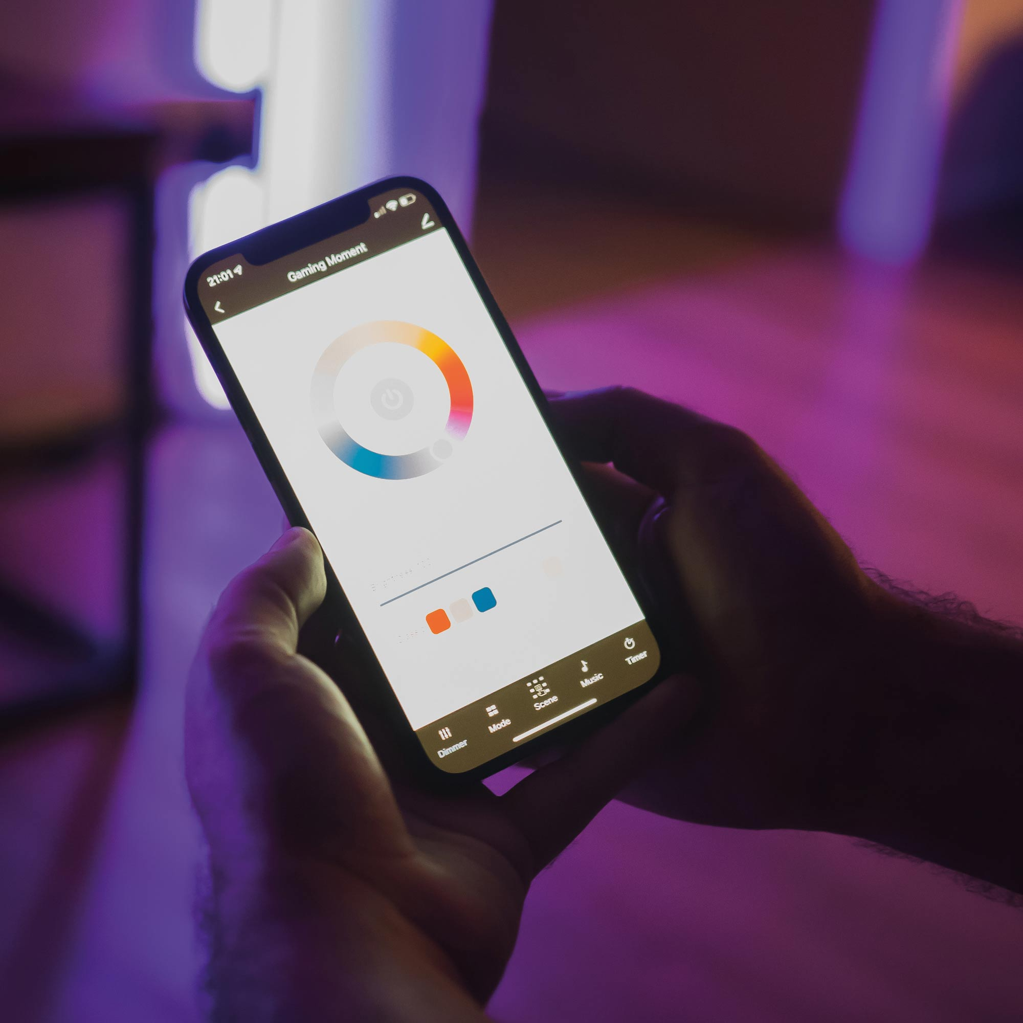 Dłonie trzymają smartfon z interfejsem koła kolorów. Fioletowe i niebieskie tło.