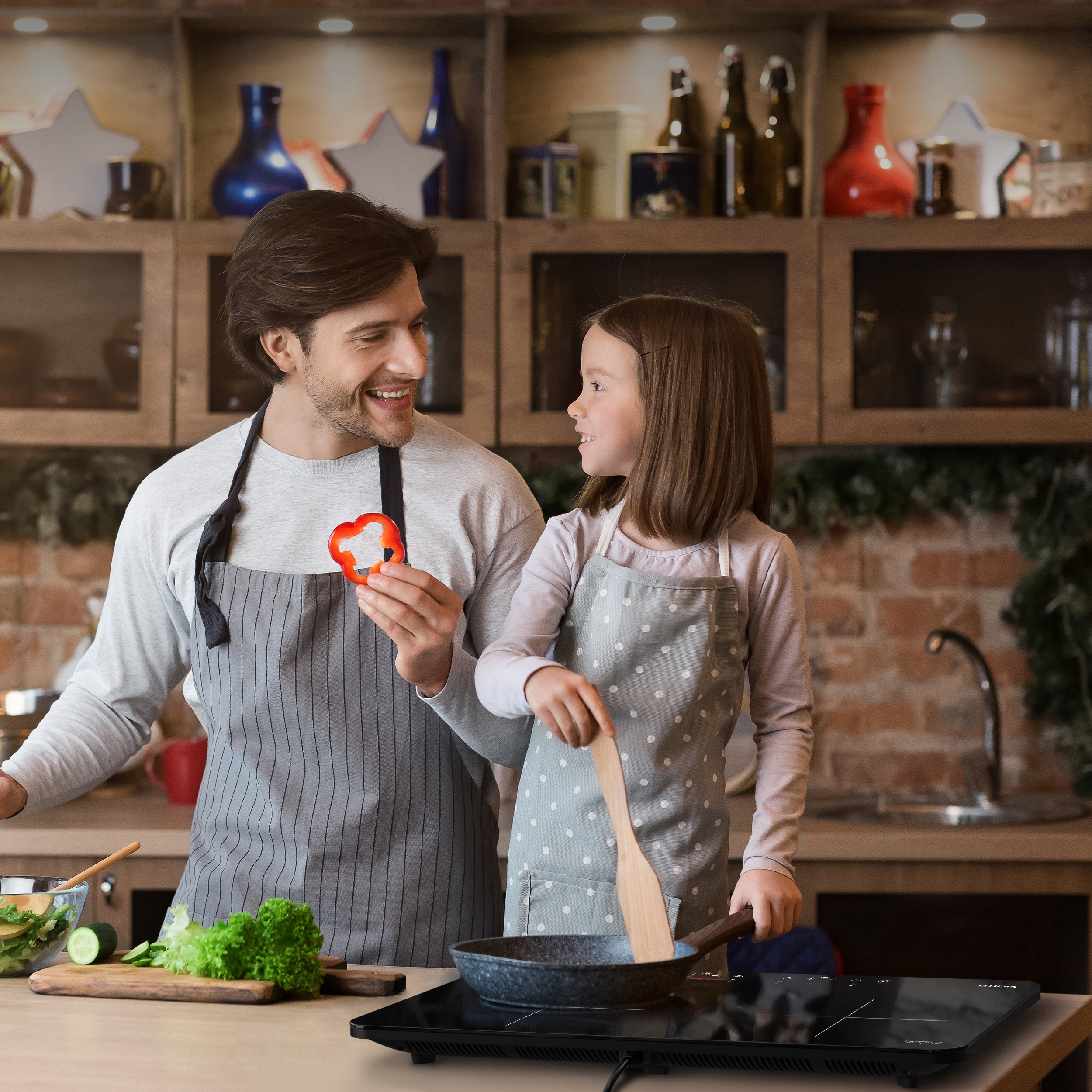 Ein Vater und eine Tochter kochen zusammen in einer Küche. Sie lächeln sich an.