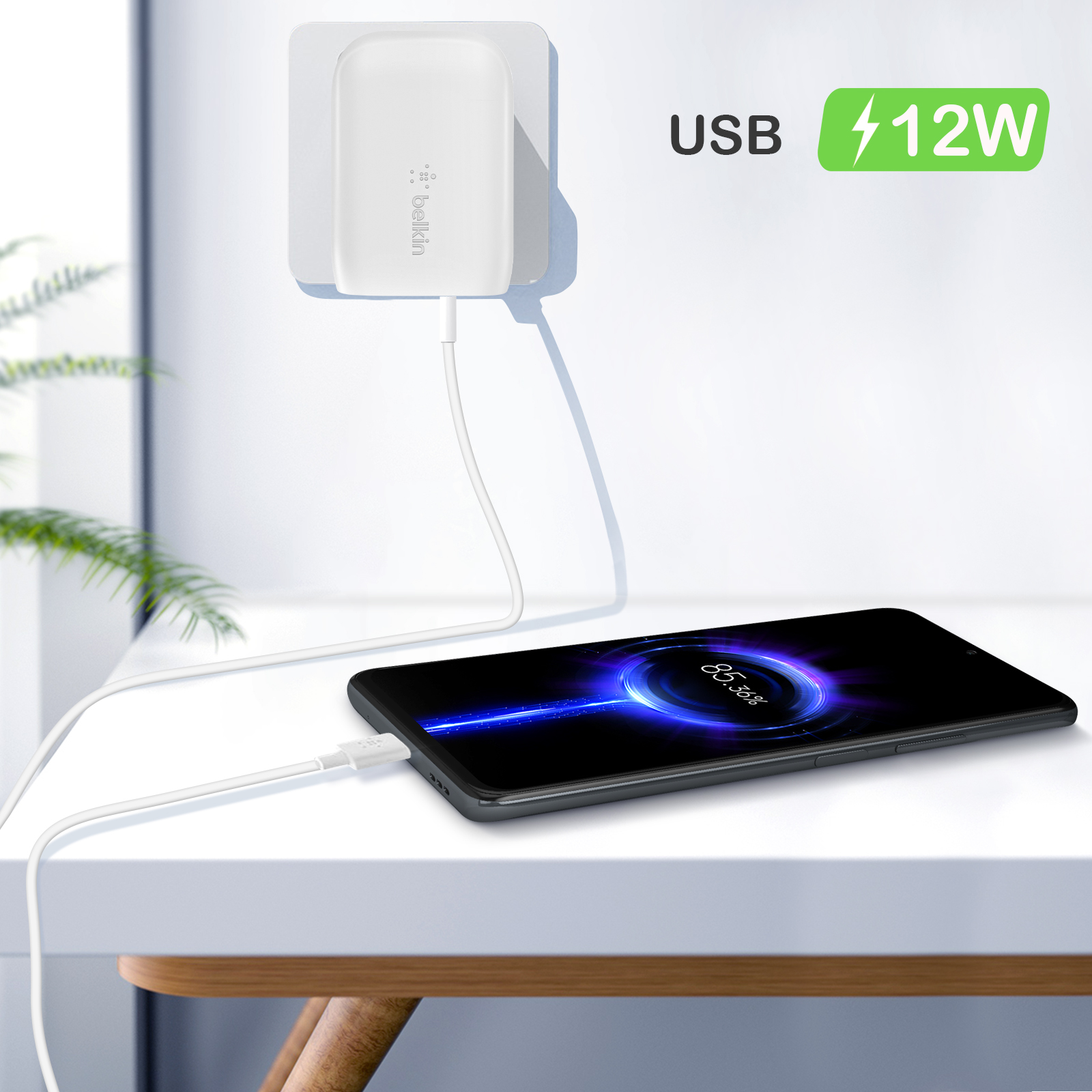 Ein weißes Belkin USB-Ladegerät eingesteckt. Telefon auf weißem Tisch laden.