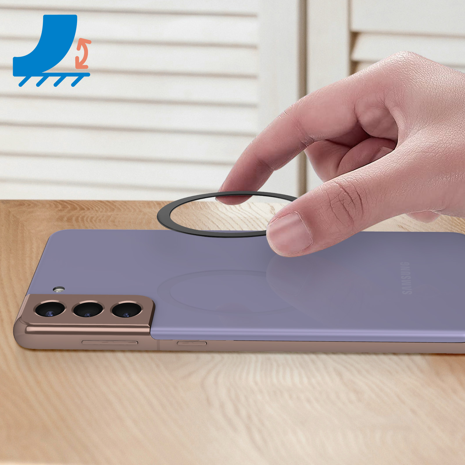 Mano che posiziona un anello nero su un telefono viola. Sfondo bianco, tavolo in legno.
