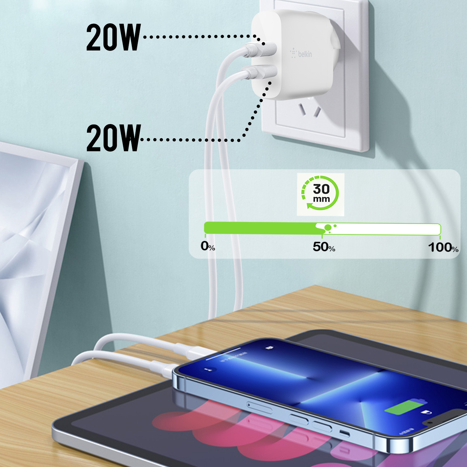 Beyaz Belkin şarj cihazı duvara takılı, iki cihazı şarj ediyor. Bir tablet ve telefon masada duruyor.