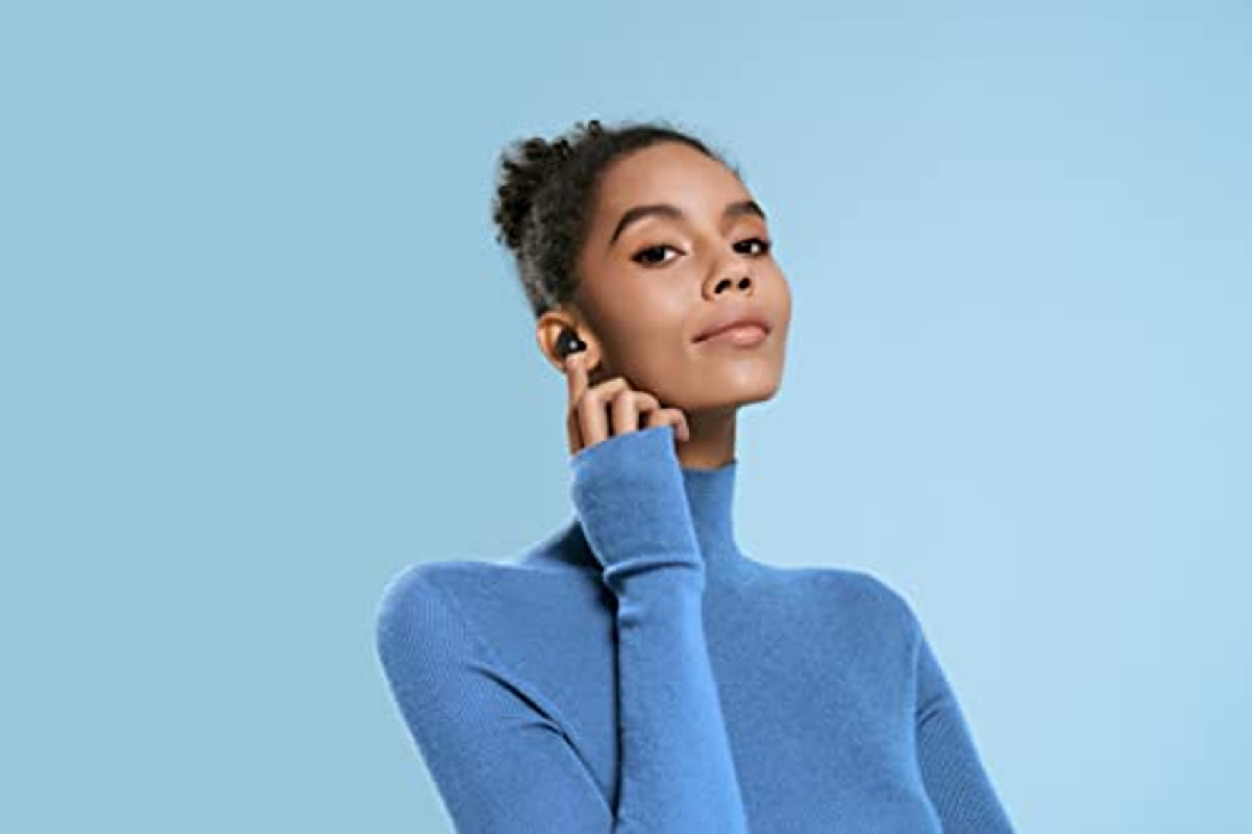 Una donna con un dolcevita blu ha un auricolare nell'orecchio.