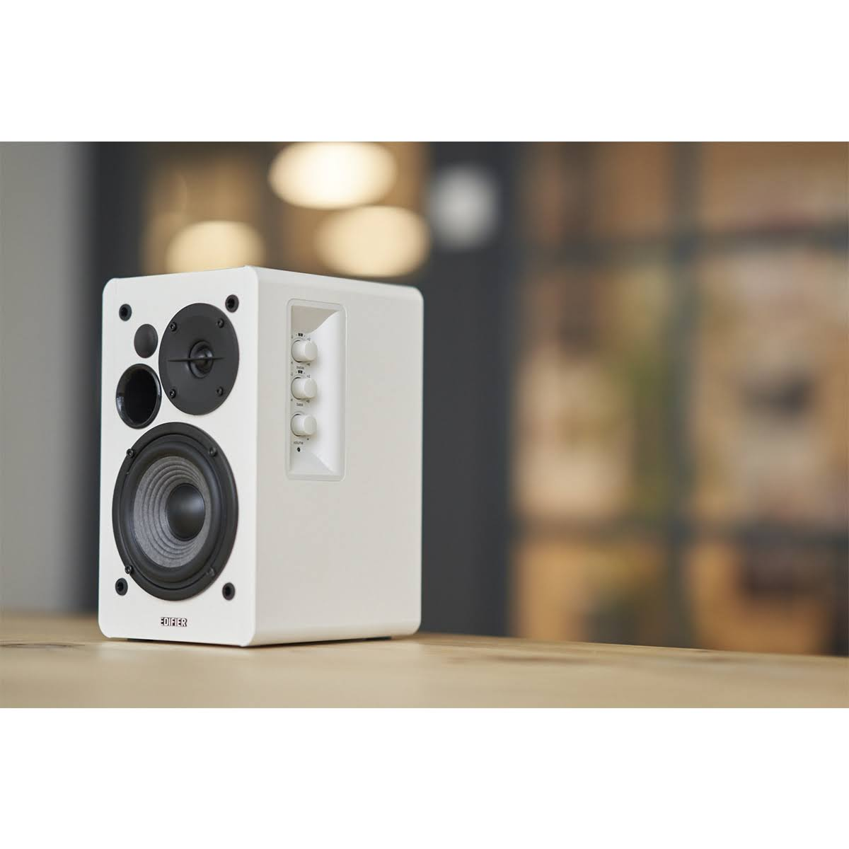 Biały głośnik Edifier na stole z rozmytym tłem.