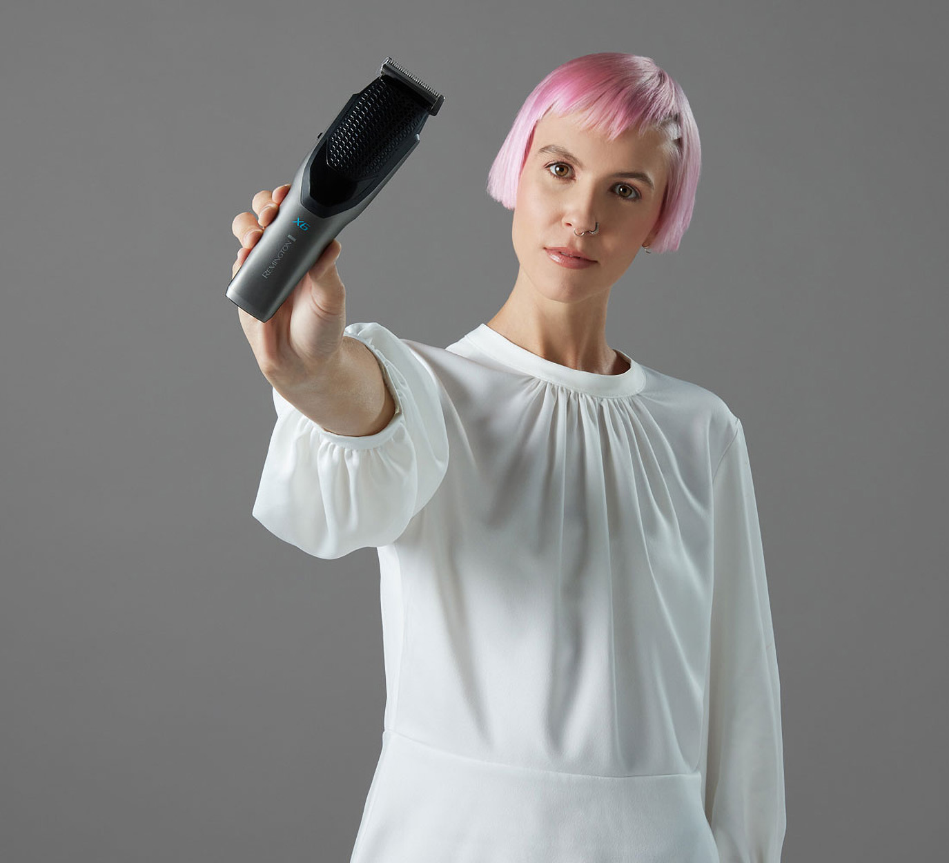 Una donna con i capelli rosa che tiene un tagliacapelli nero.