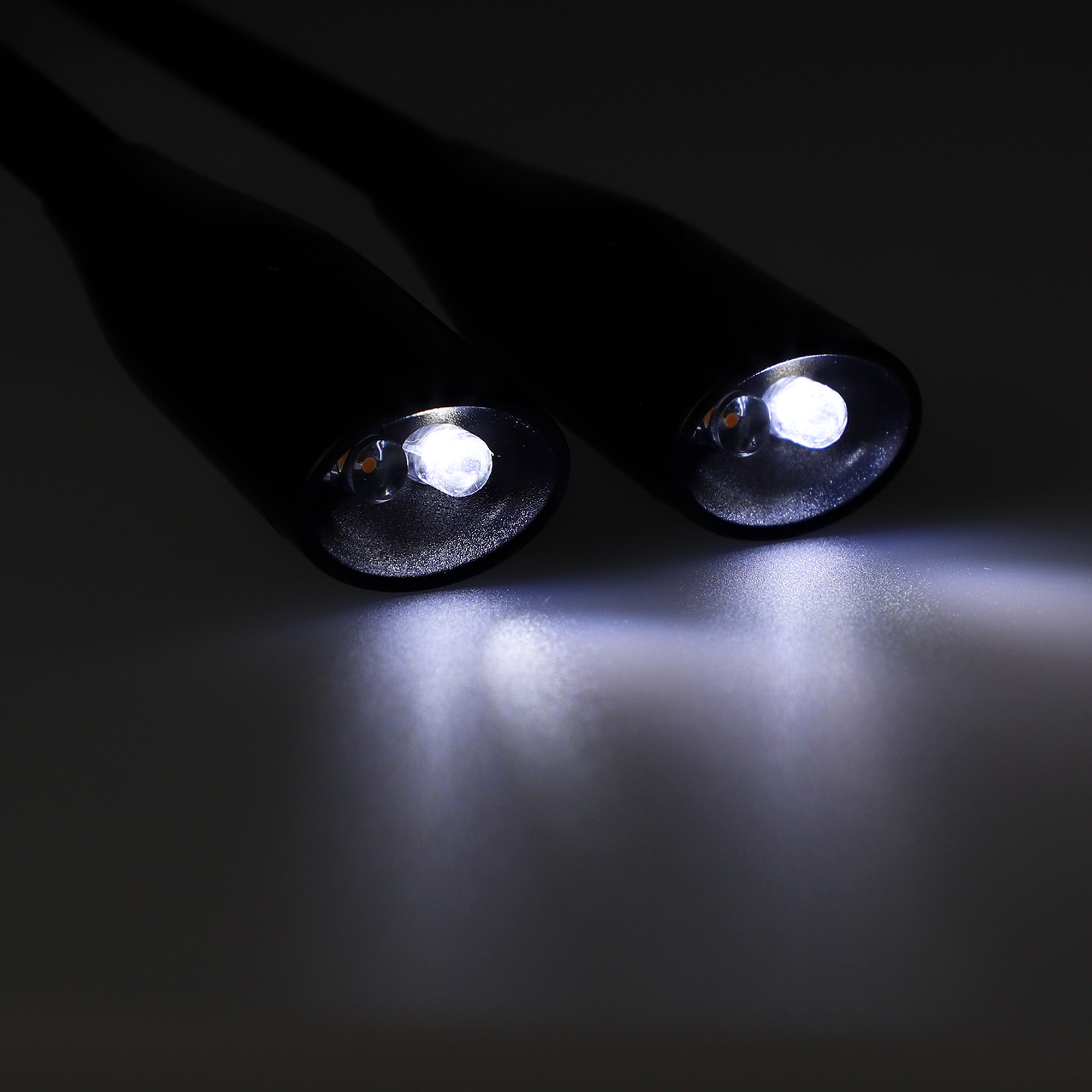 Dos luces negras sobre un fondo oscuro. Las luces están encendidas y apuntando al espectador.