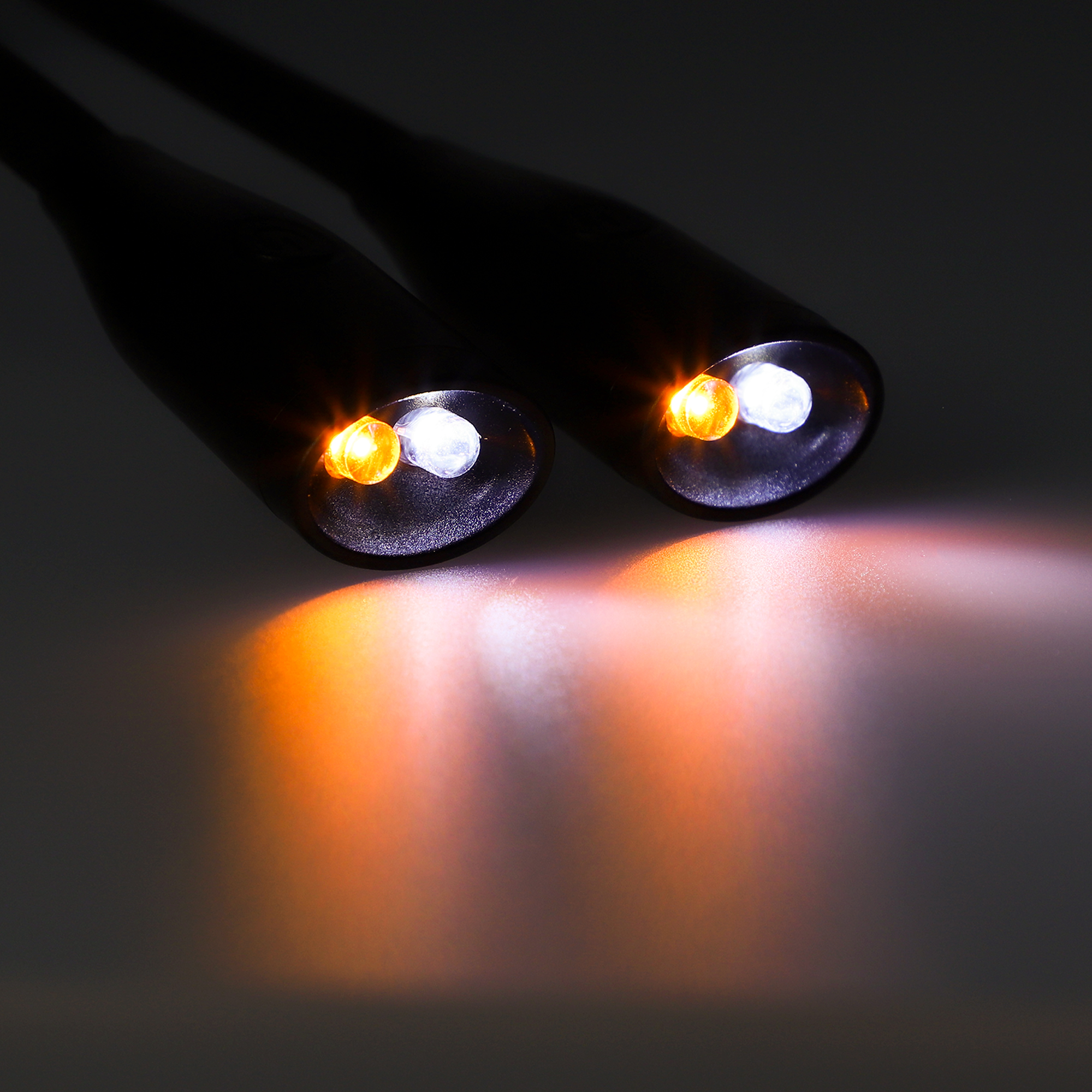 Dos luces LED negras apuntan hacia el espectador. Las luces son amarillas y blancas.