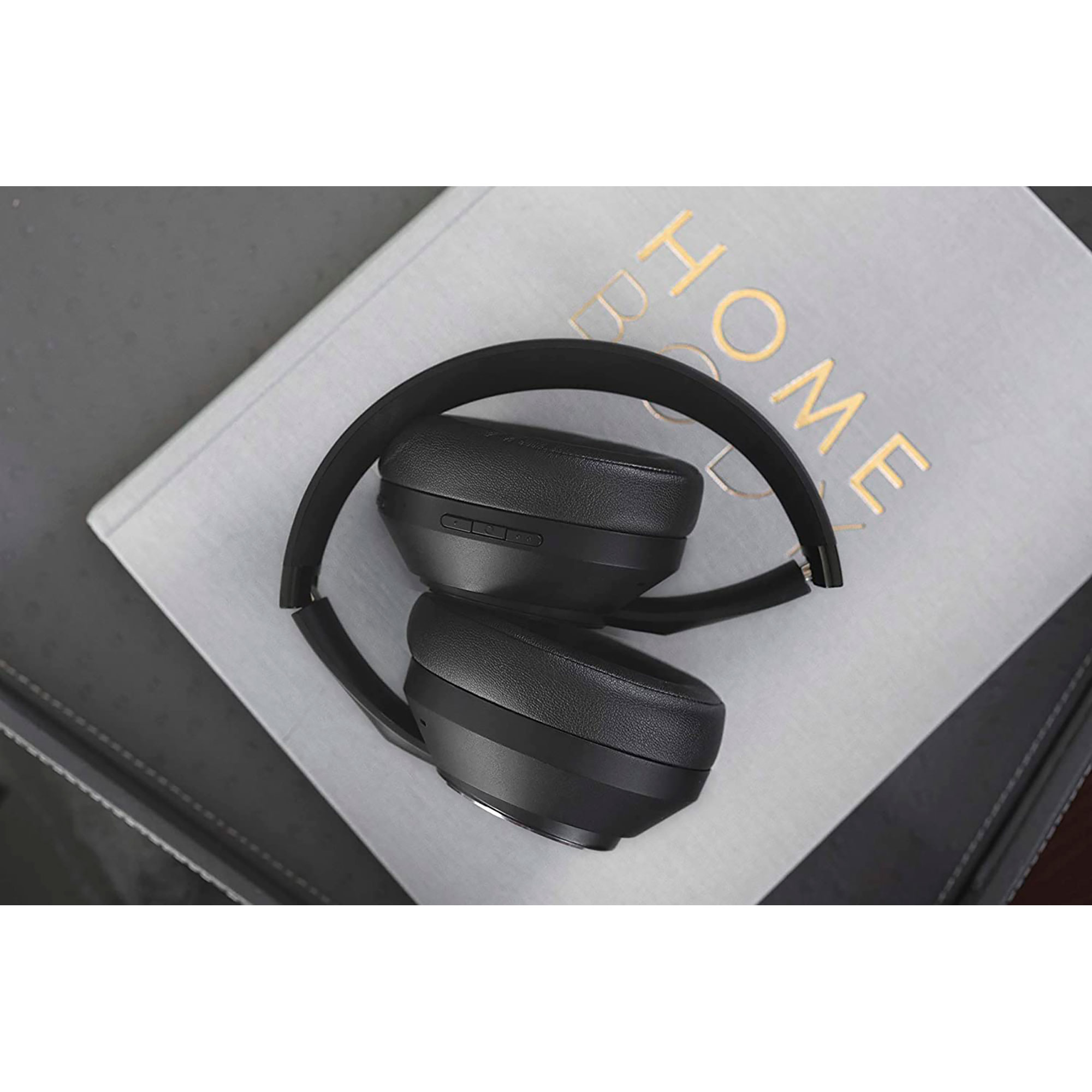 Casque noir sur un livre gris sur une surface sombre. Le casque est plié.
