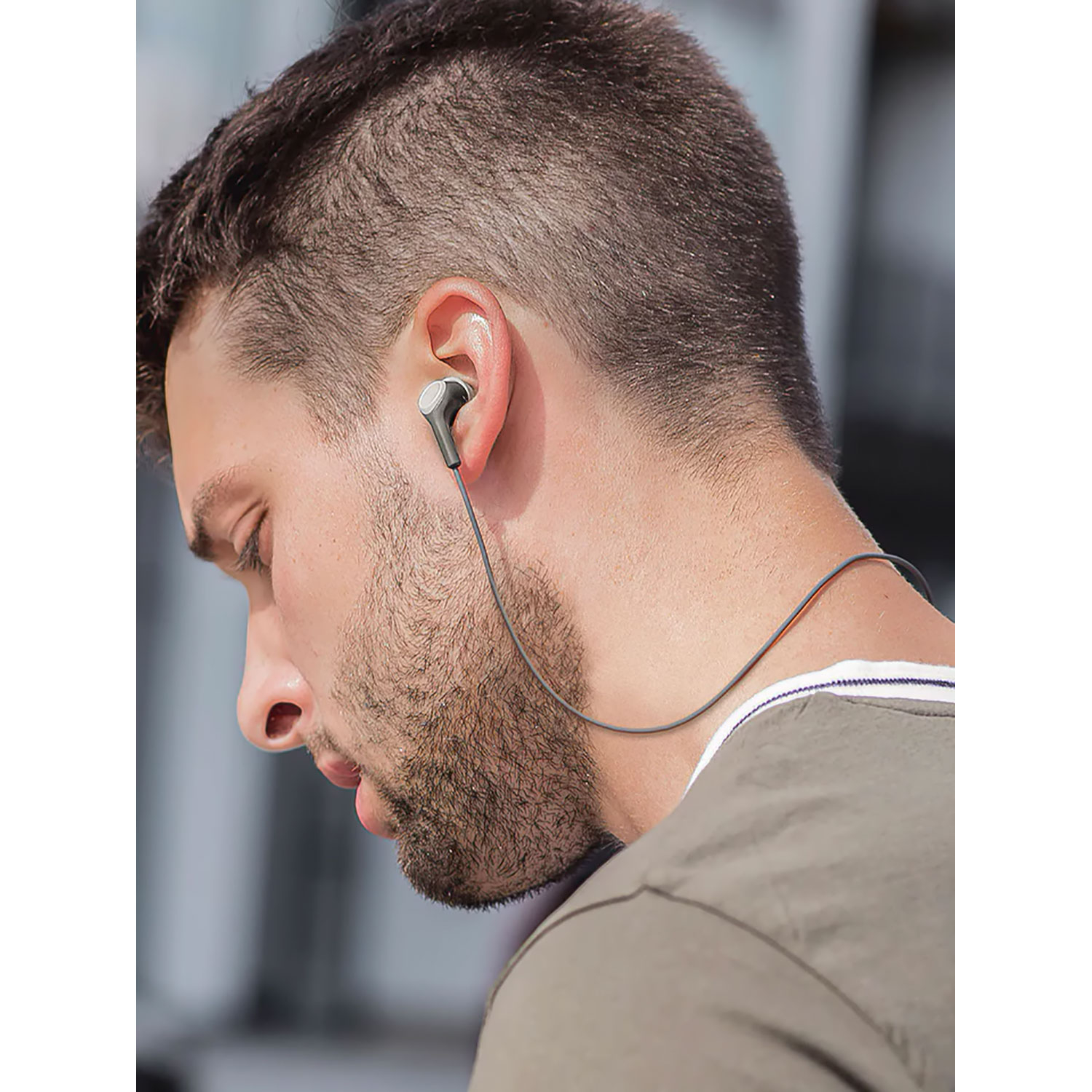 Uomo con auricolare. L'auricolare è grigio e collegato a un filo.