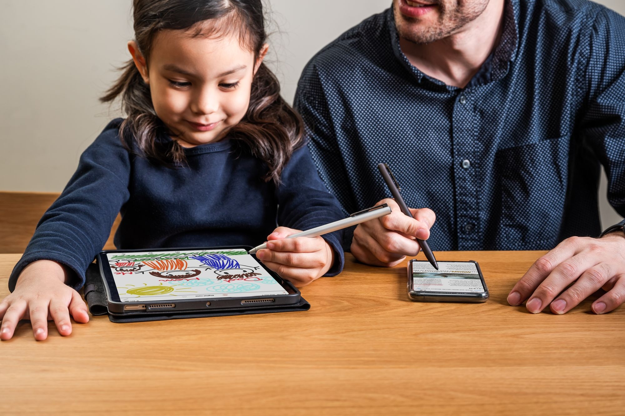 Una ragazza e un uomo che disegnano su tablet e telefono con stilo.