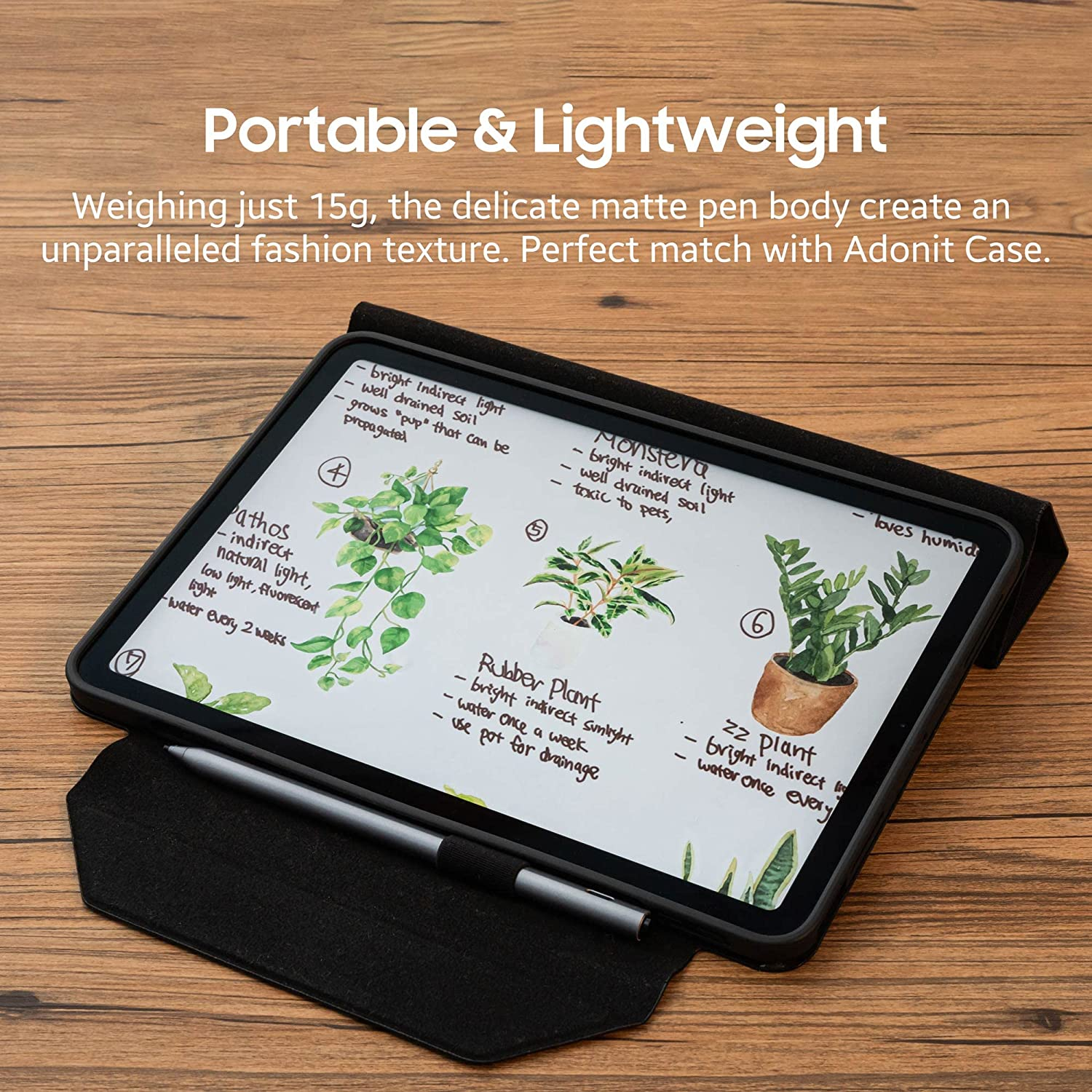 Tablet con appunti manoscritti sulle piante. Custodia nera, superficie in legno. Penna attaccata.