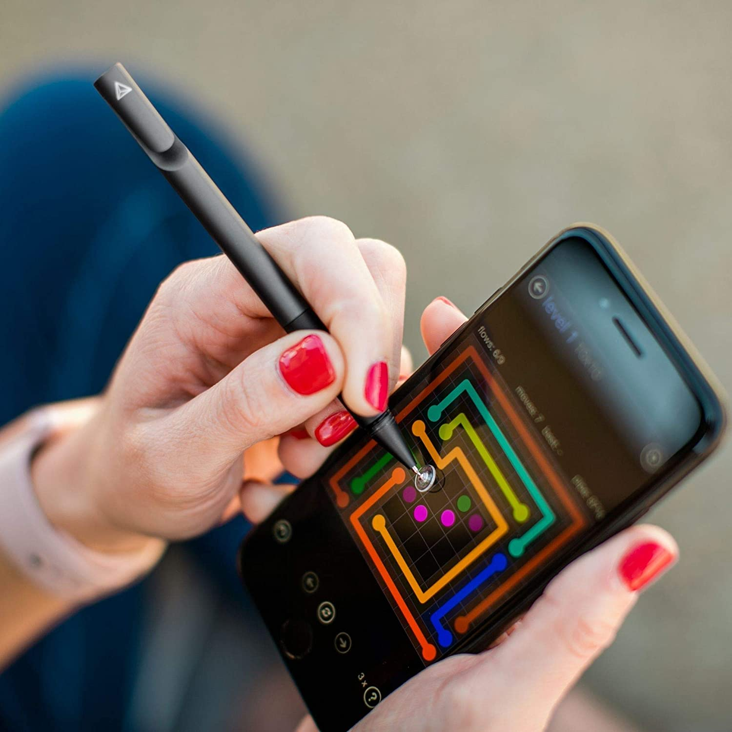 Mani che tengono uno smartphone nero, che gioca a un gioco con linee colorate. Una penna stilo viene utilizzata per interagire.