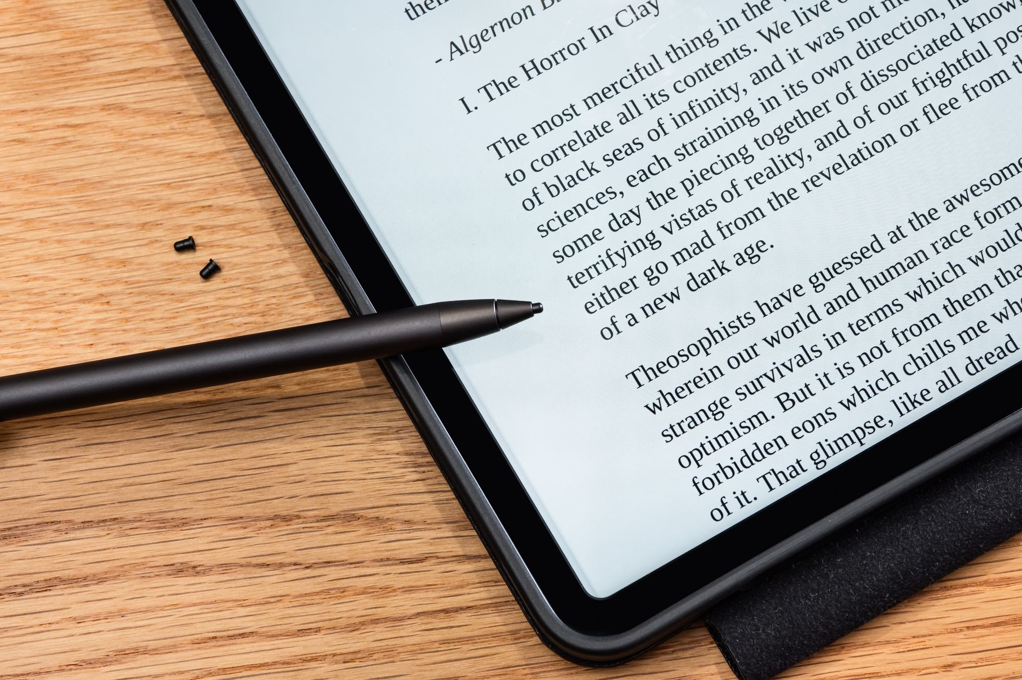 Un tablet nero con uno stilo su un tavolo di legno, che mostra il testo di un libro.