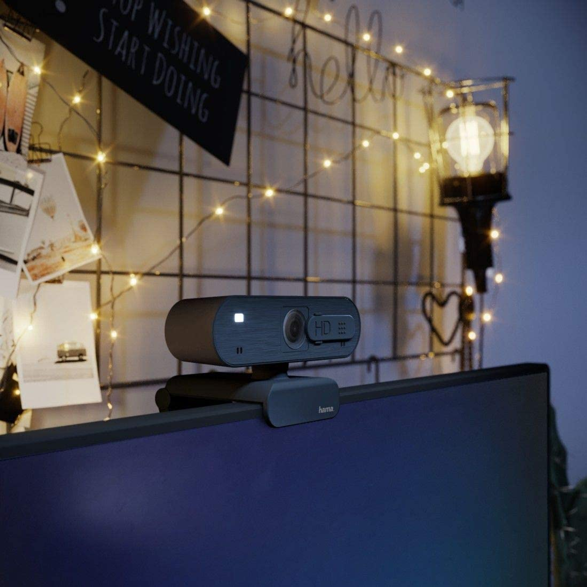 Kamera internetowa na monitorze. Kamera internetowa jest szara z czarnym klipsem. Ciemne tło.