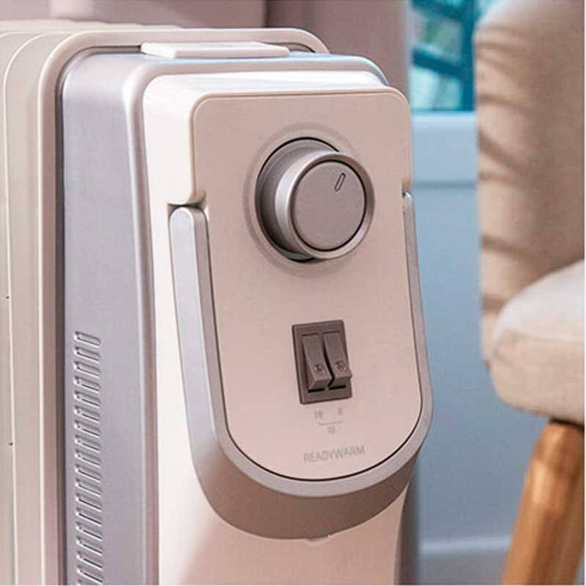 Zbliżenie kremowego panelu sterowania grzejnikiem z pokrętłem i przełącznikami.