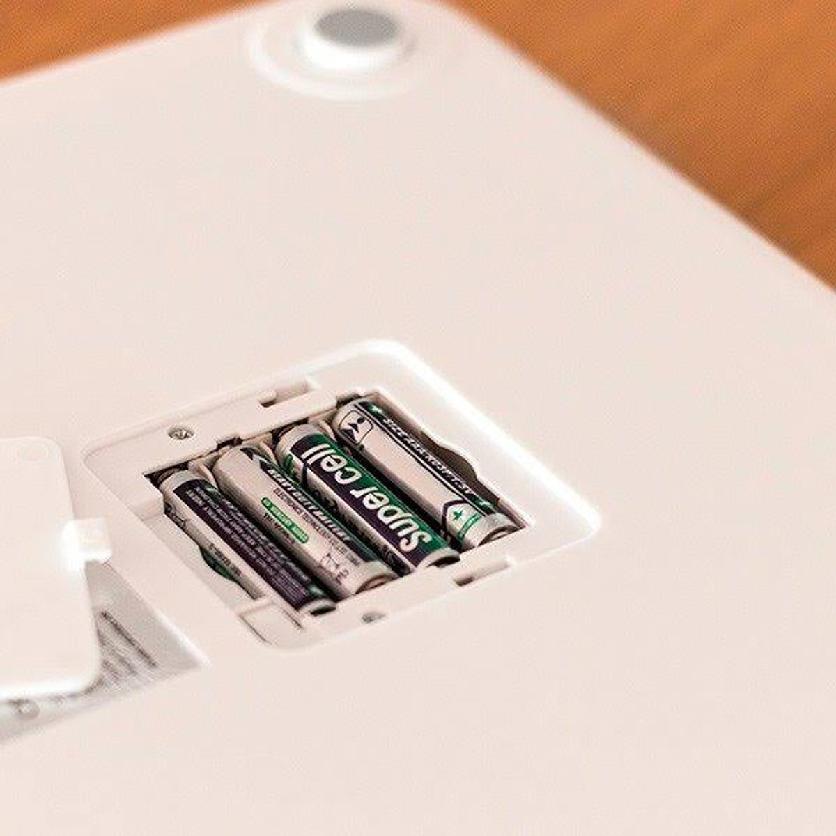 Rückseite einer weißen Waage mit Batterien im Batteriefach, Nahaufnahme.