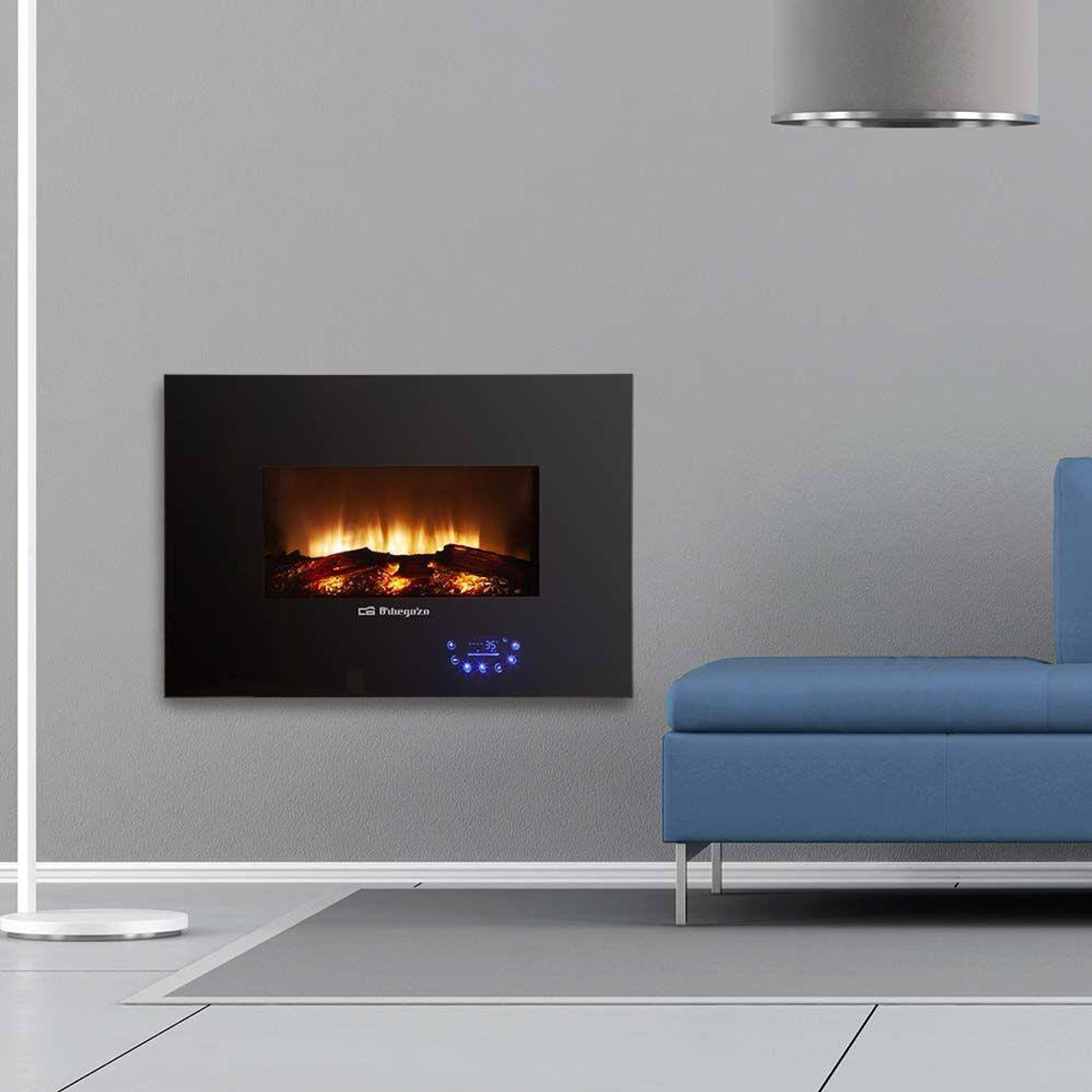 Una chimenea eléctrica montada en la pared con marco negro, sofá azul y pared gris.