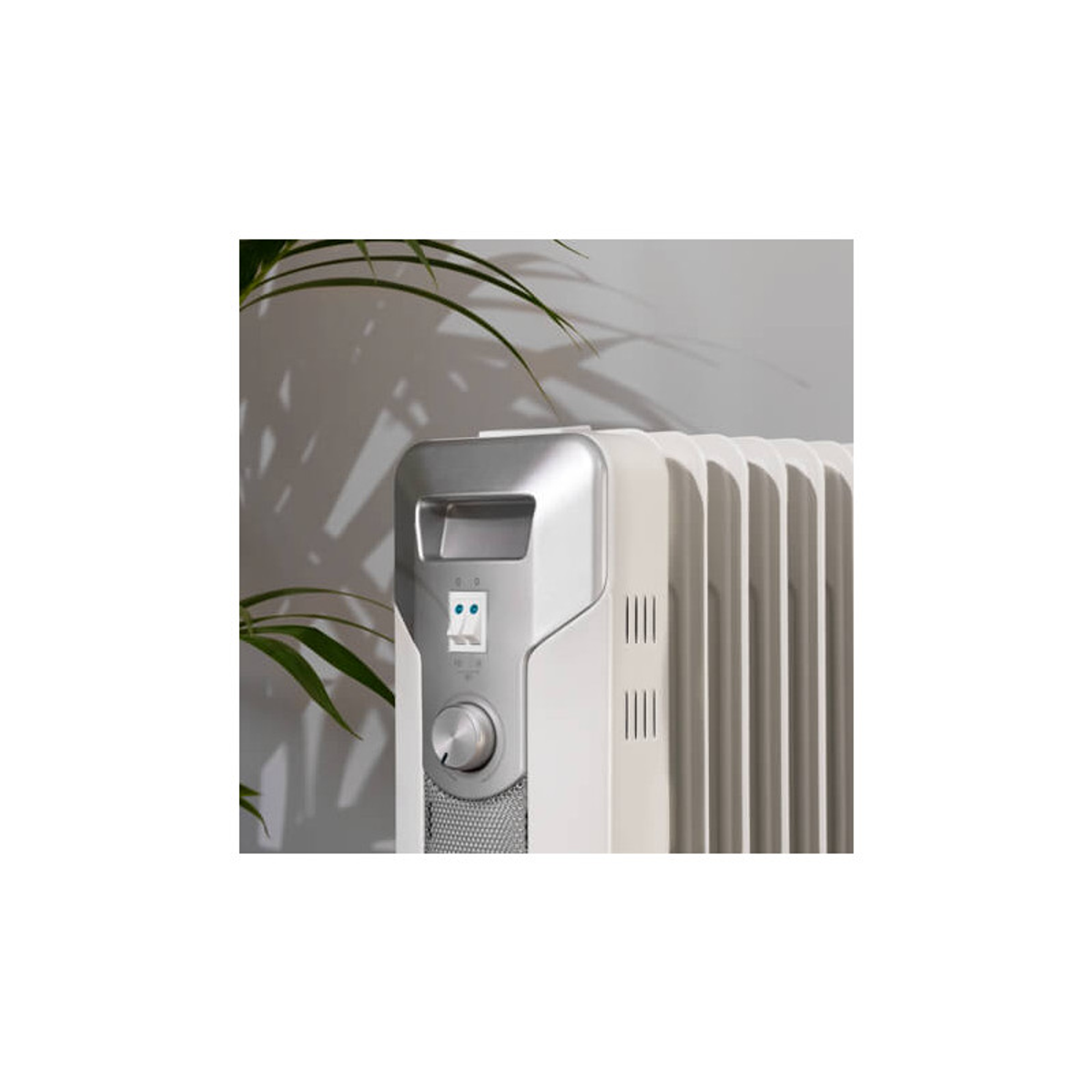 Biały i srebrny grzejnik z panelem sterowania. Zielona roślina w tle.