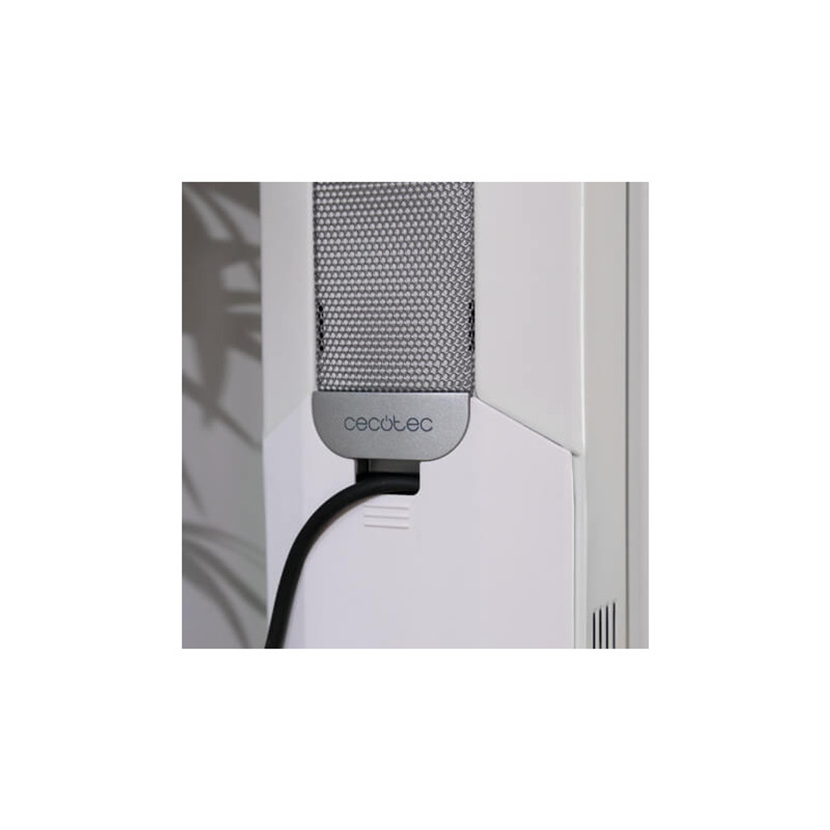 Zbliżenie białego oczyszczacza powietrza z czarnym kablem. Oczyszczacz posiada srebrną kratkę.