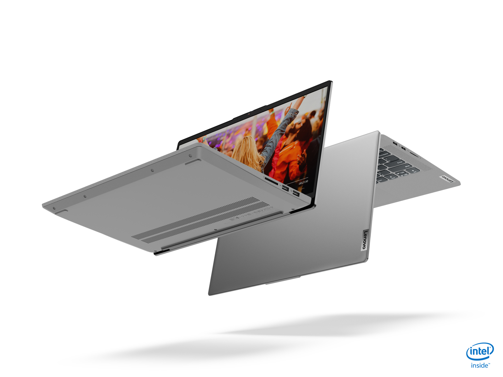 Dos portátiles Lenovo grises flotando en el aire. Uno abierto, mostrando un concierto, el otro cerrado, con el logo de Lenovo.