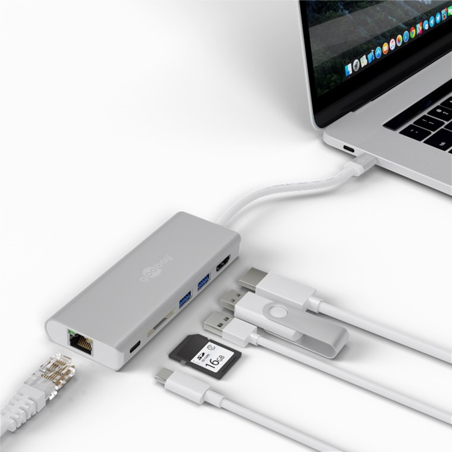 Un laptop con un hub collegato, vari cavi e una scheda SD.