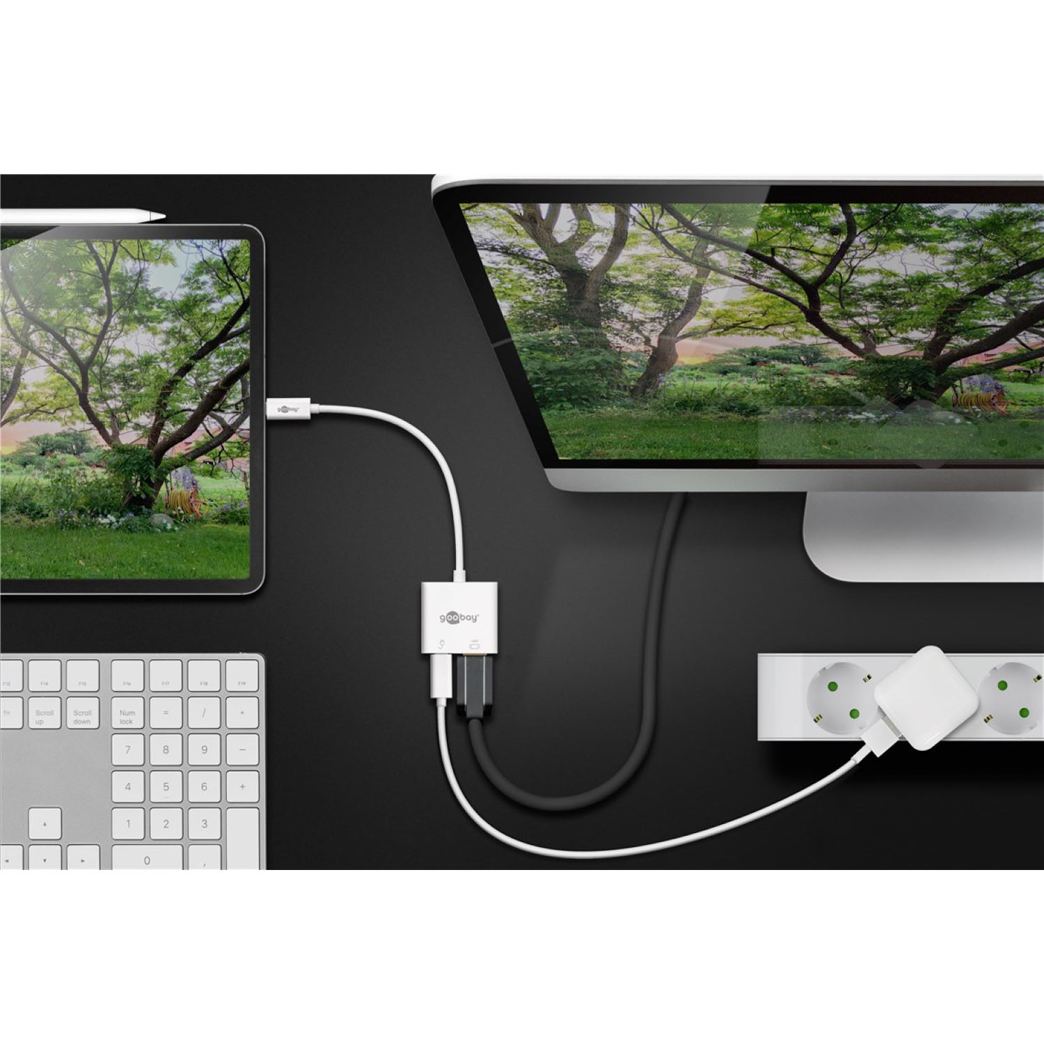 Tablet e monitor collegati tramite un adattatore bianco. Tastiera, mouse e presa multipla sono visibili.