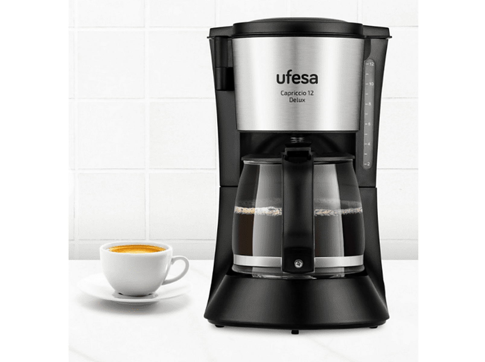 Czarny i srebrny ekspres do kawy, biały kubek z kawą na białym talerzu. Tło z białych płytek.