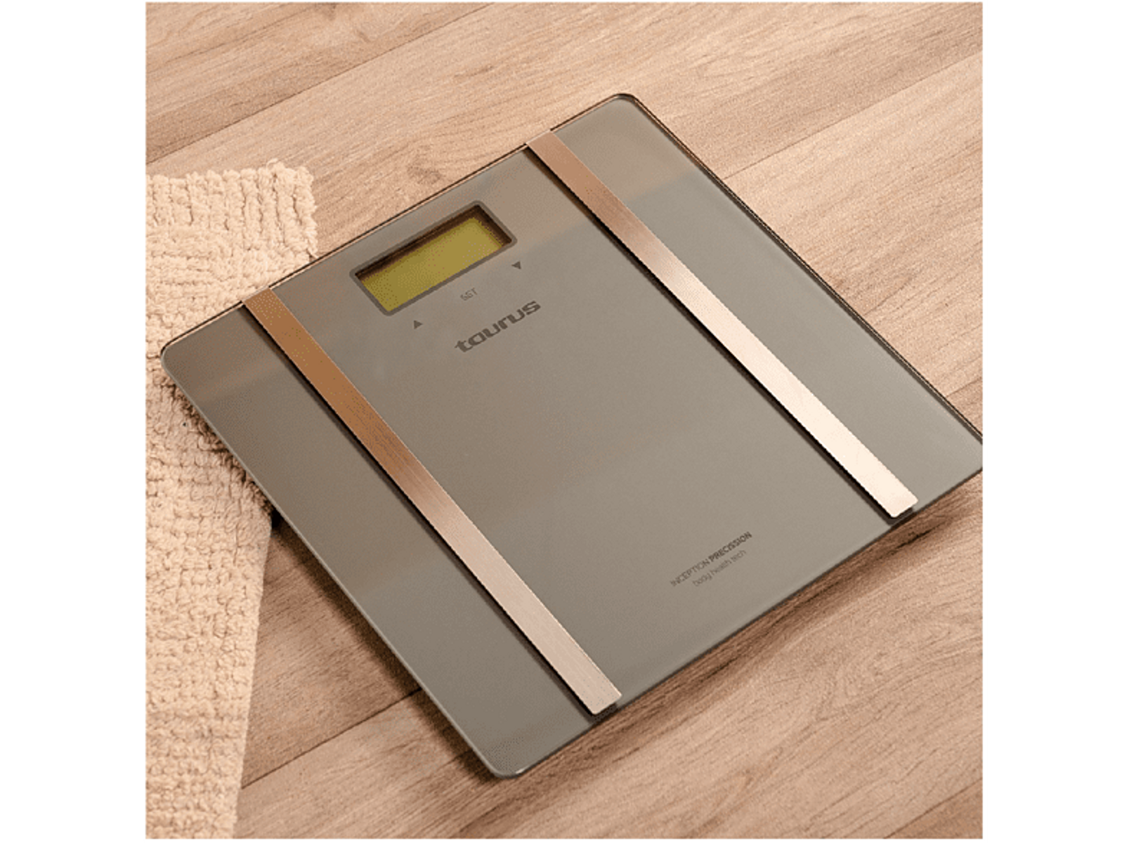 Waga cyfrowa ze szklaną powierzchnią i srebrnymi akcentami na drewnianej powierzchni z białym ręcznikiem z boku.