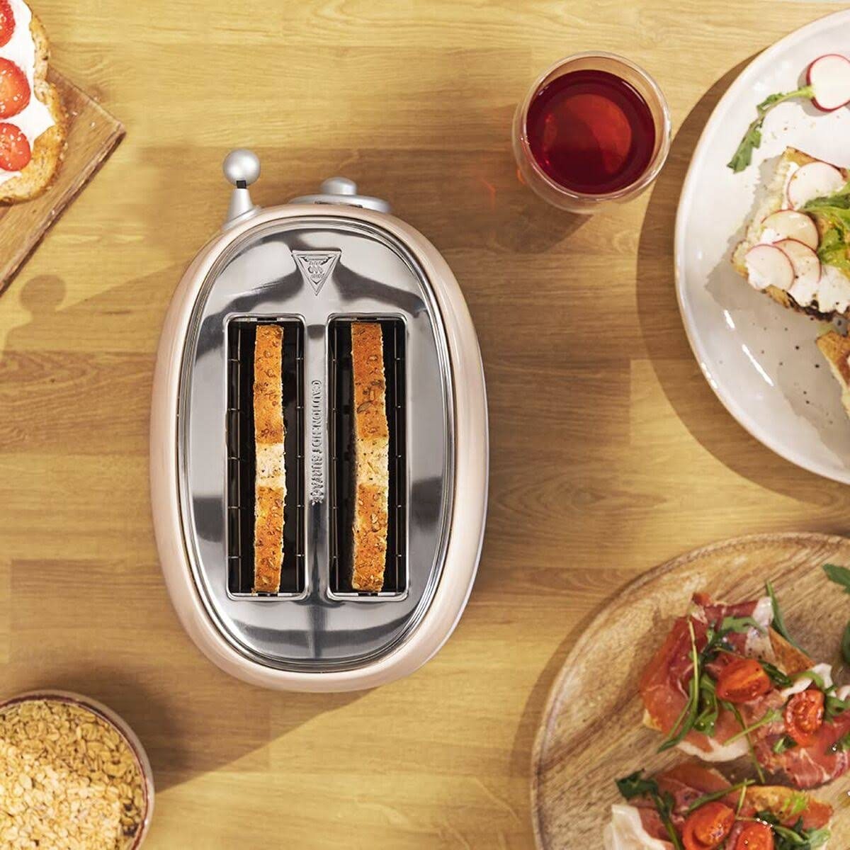 Toaster mit zwei Toastscheiben. Teller mit Essen umgeben ihn. Hintergrund ist ein Holztisch.