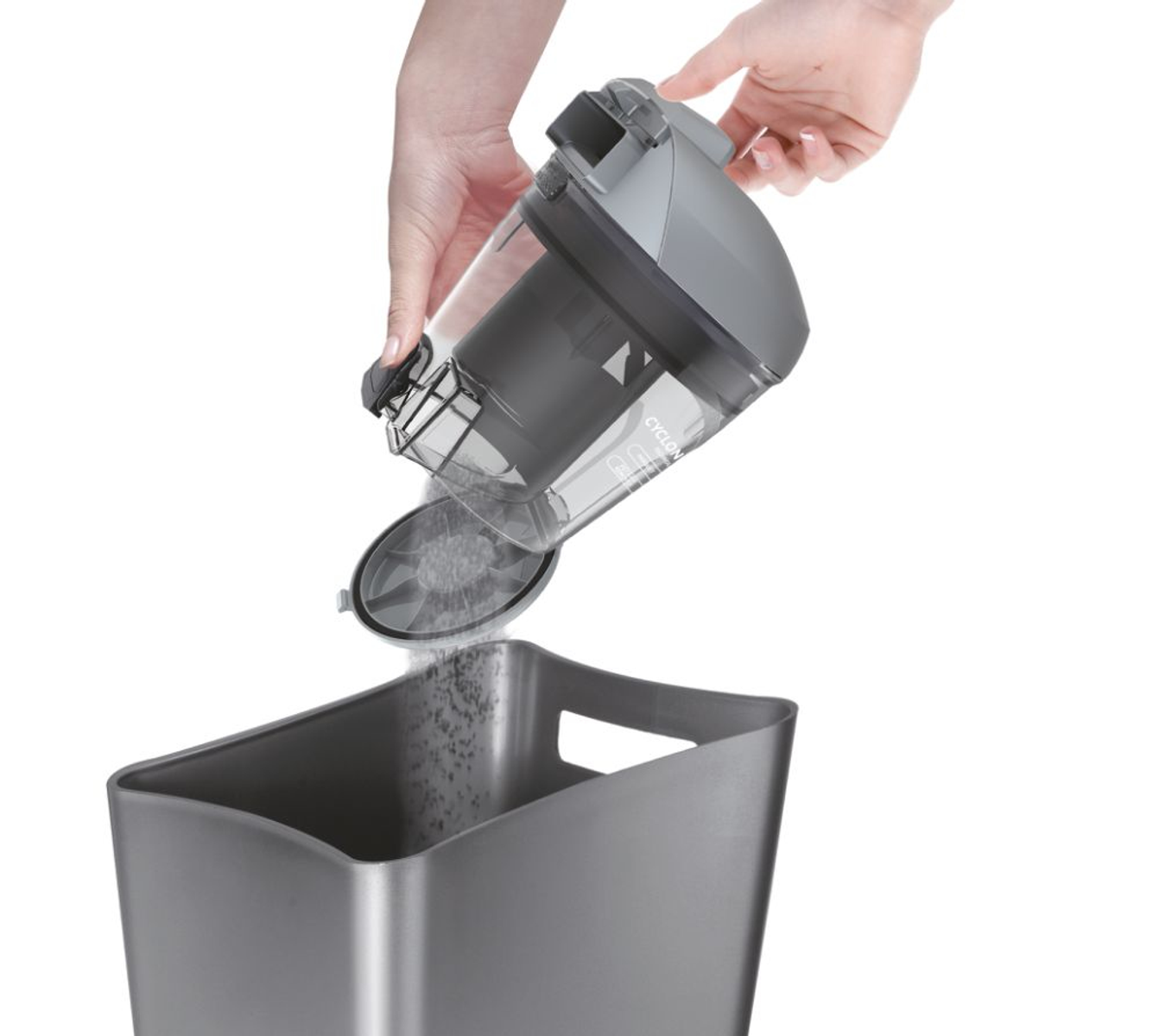 Osoba opróżnia pojemnik na kurz odkurzacza do kosza na śmieci. Widoczny kurz.