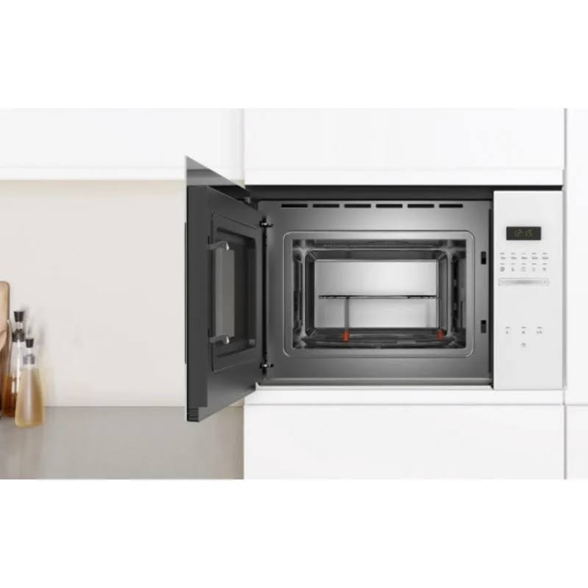Otwarty piekarnik mikrofalowy wbudowany w białą szafkę. Drzwi są otwarte. Wnętrze jest widoczne.