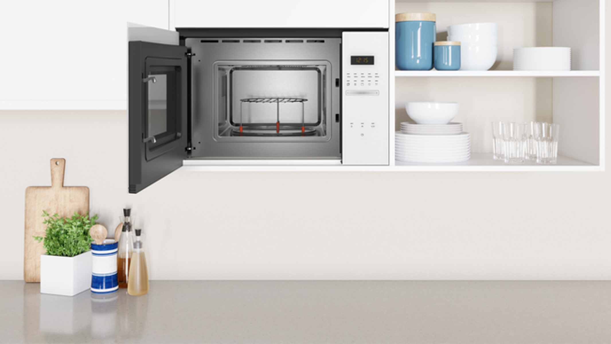 Otwarta kuchenka mikrofalowa w białej kuchni z półkami i blatem.